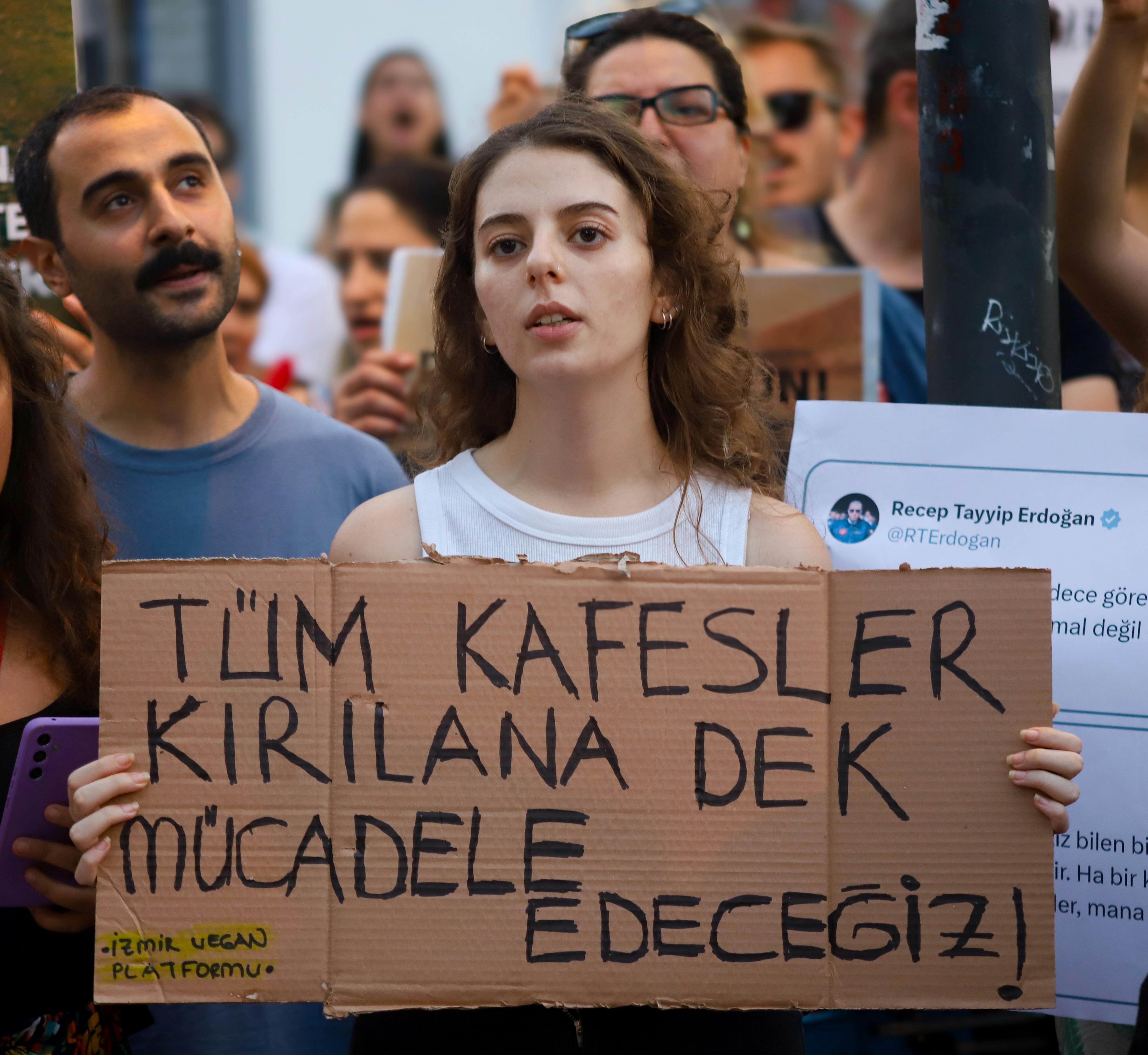 a woman holding a sign that says tim kafesleri kirilin dekad