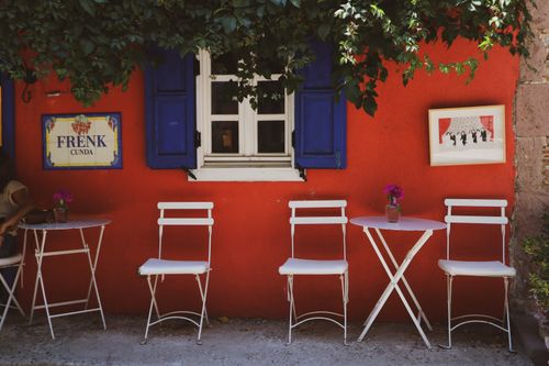 Free Vibrant outdoor cafe scene with white furniture set against colorful walls, perfect for a relaxing day. Stock Photo