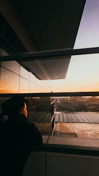 Man gazing at sunset reflection on a modern urban building facade in Davao City.