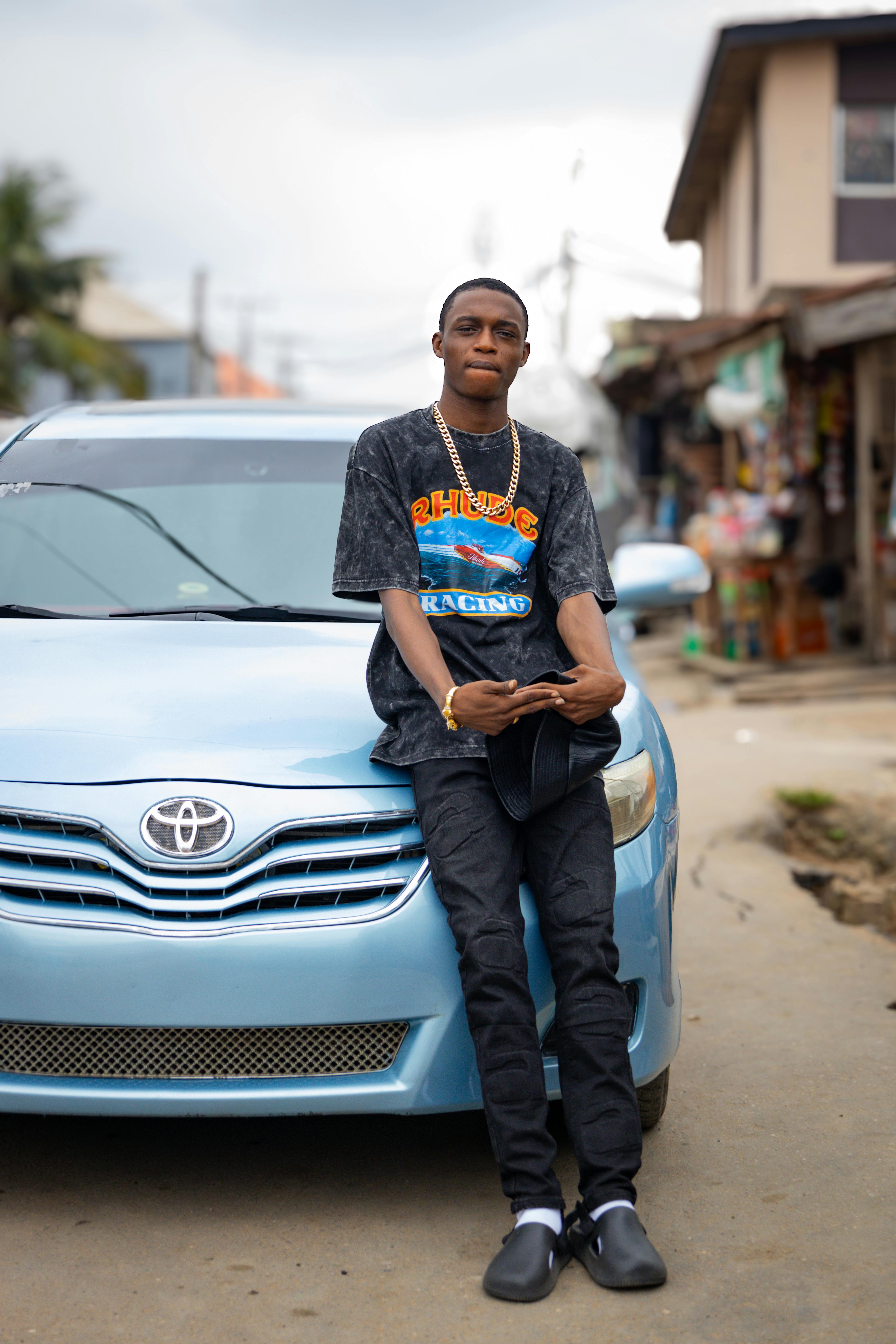 a young man sitting on the hood of a blue car