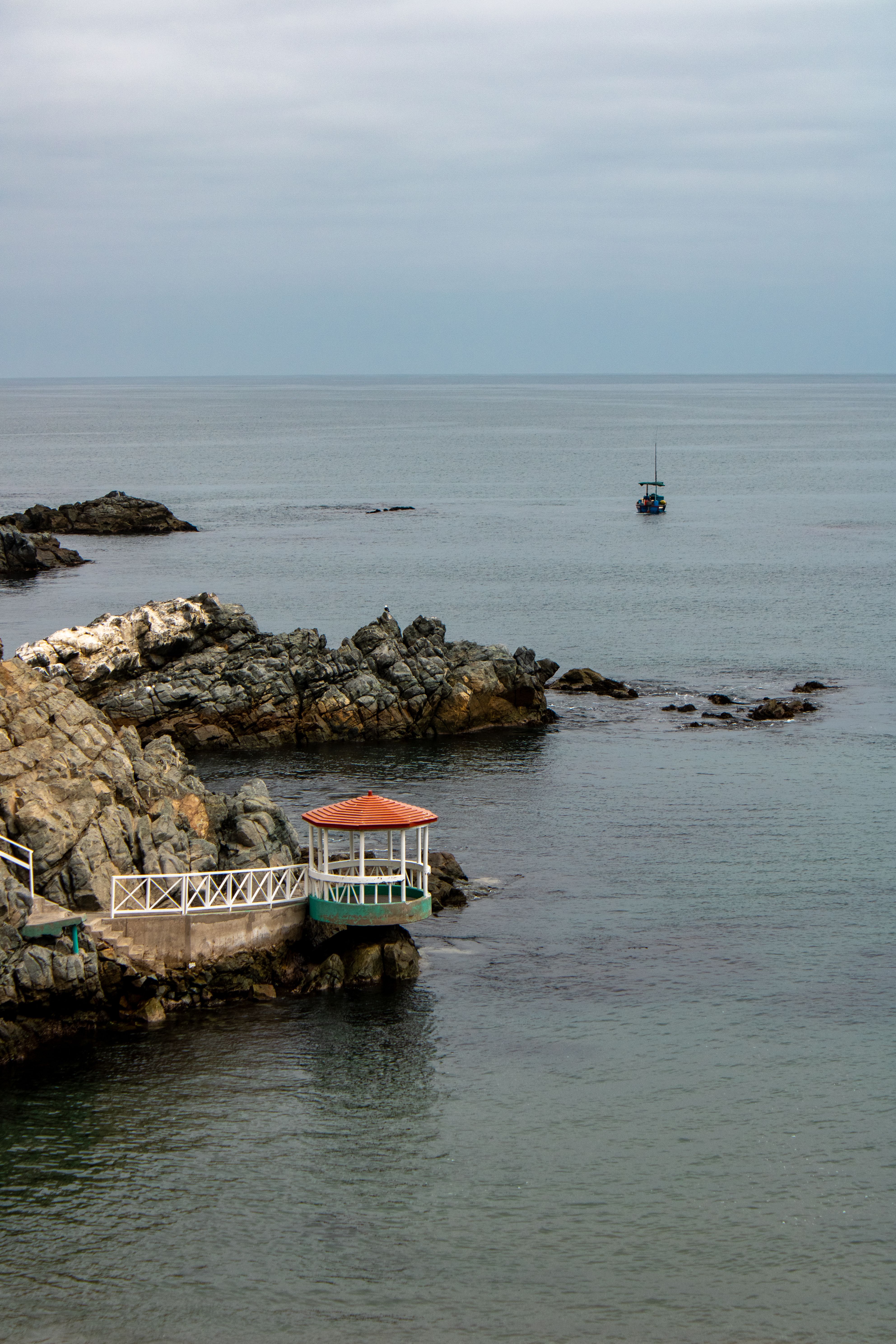 Explore the tranquil rocky coastline and pavilion in Ilo, Perú, showcasing serene ocean views.