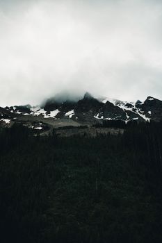 Moody mountain landscape in Banff, Canada with fog and snow-capped peaks.