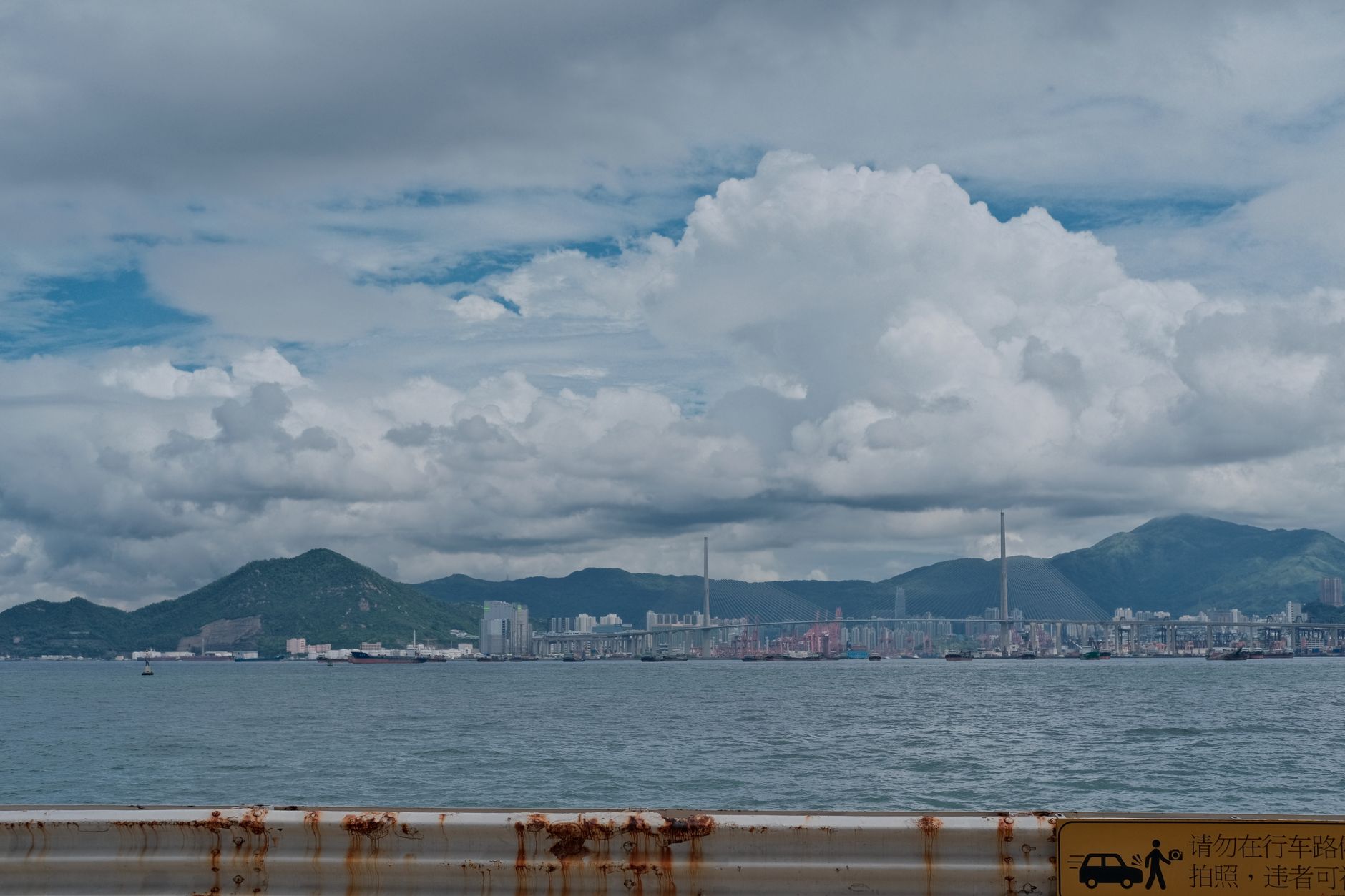 Dramatic cityscape with ocean and mountains under cloudy sky.