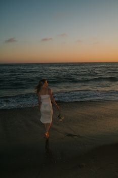 A woman walks along Laguna Beach at sunset, creating a serene and tranquil scene.