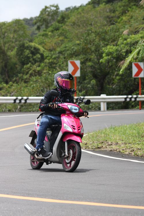 A person riding a pink motorcycle on a road · Free Stock Photo