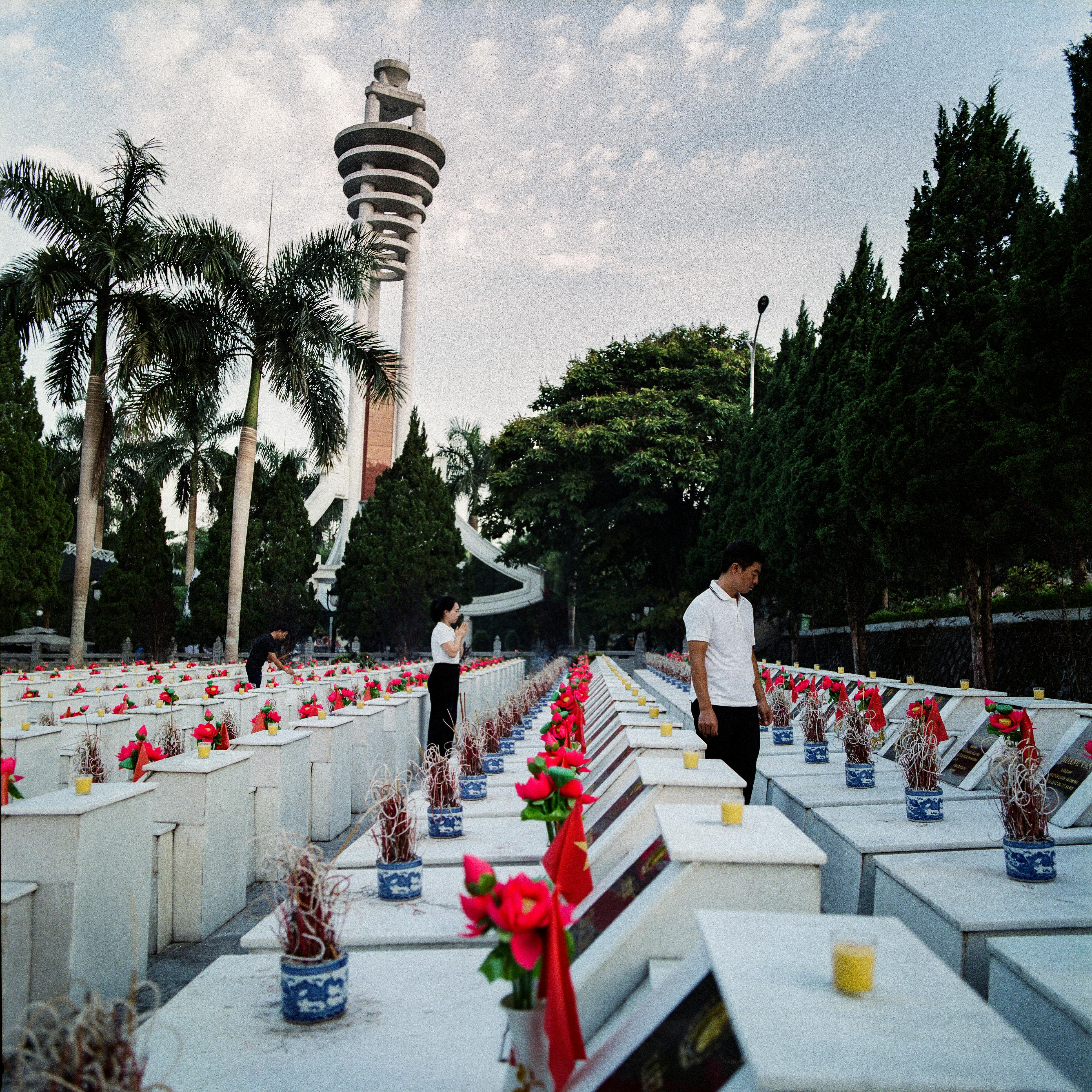 Visitors honoring fallen soldiers at a serene war memorial cemetery.