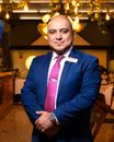 Portrait of a confident businessman in a restaurant, elegantly dressed in a blue suit and pink tie.