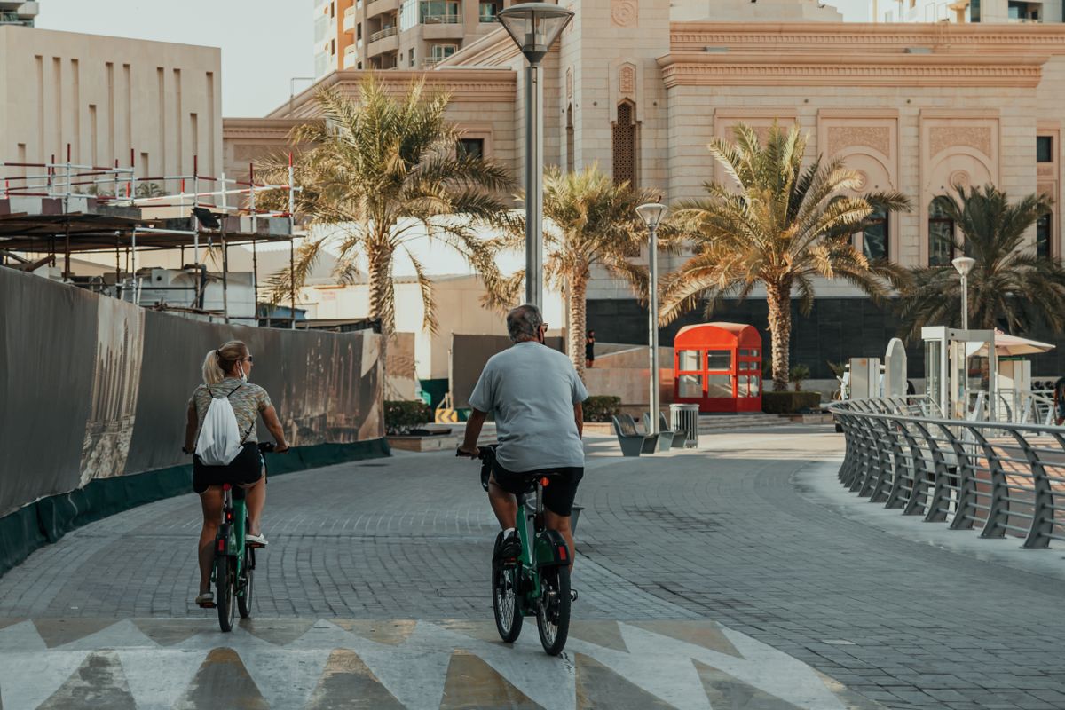 Cyclists on a wide waterfront path in Dubai with the sea in the background