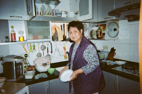 Free An elderly woman preparing a meal in a modern kitchen with various utensils. Stock Photo