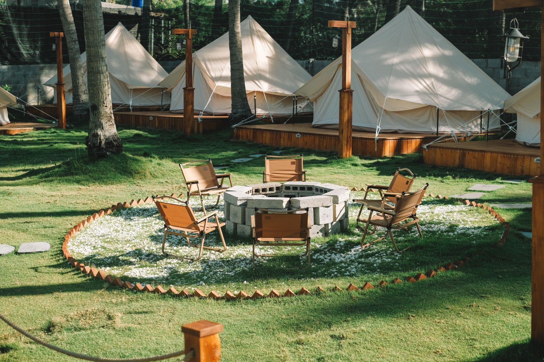 Explore a serene glamping site in Phan Thiet, Vietnam featuring stylish tents and a cozy fire pit area.