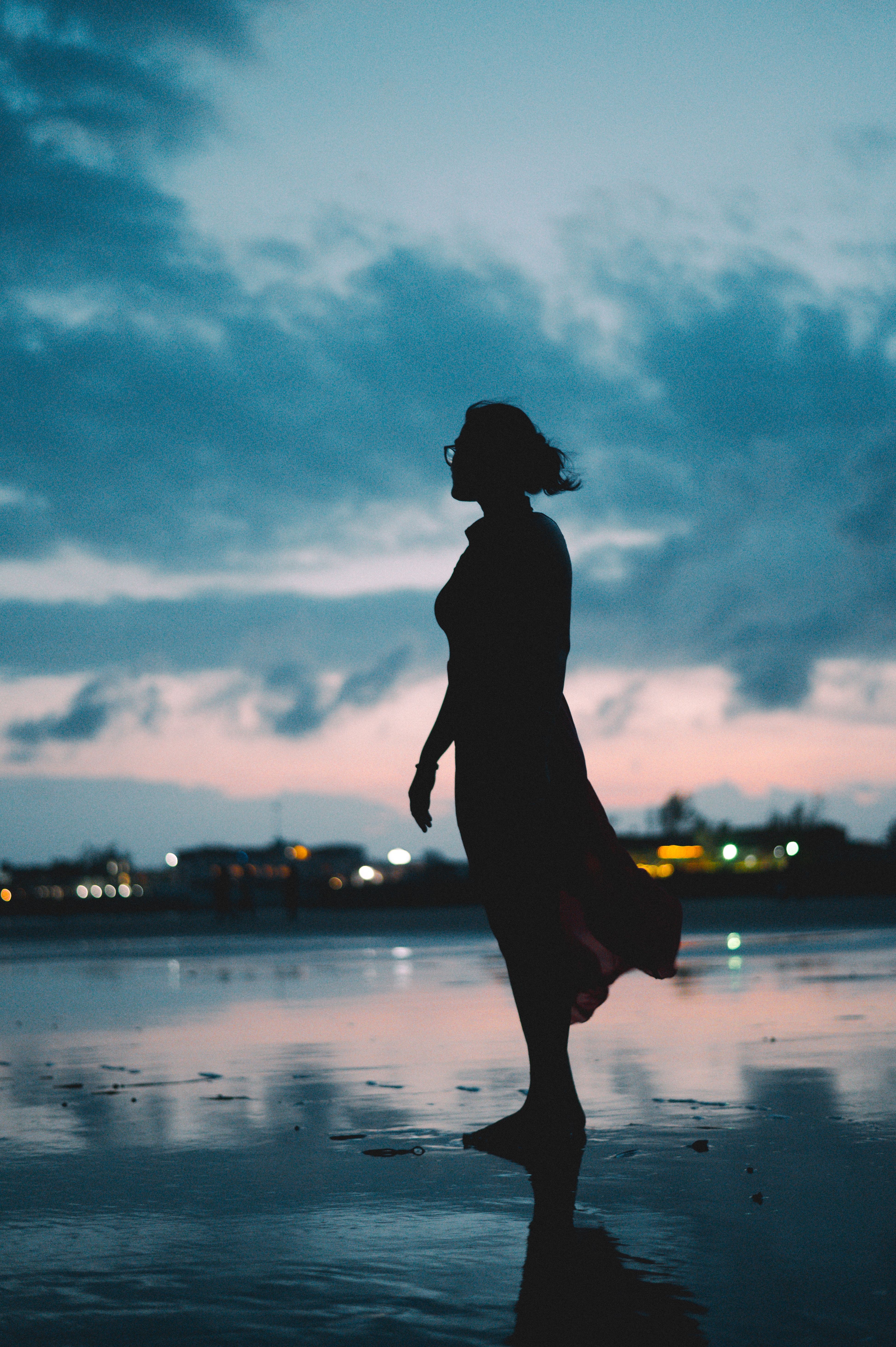 A woman standing on the beach at sunset · Free Stock Photo