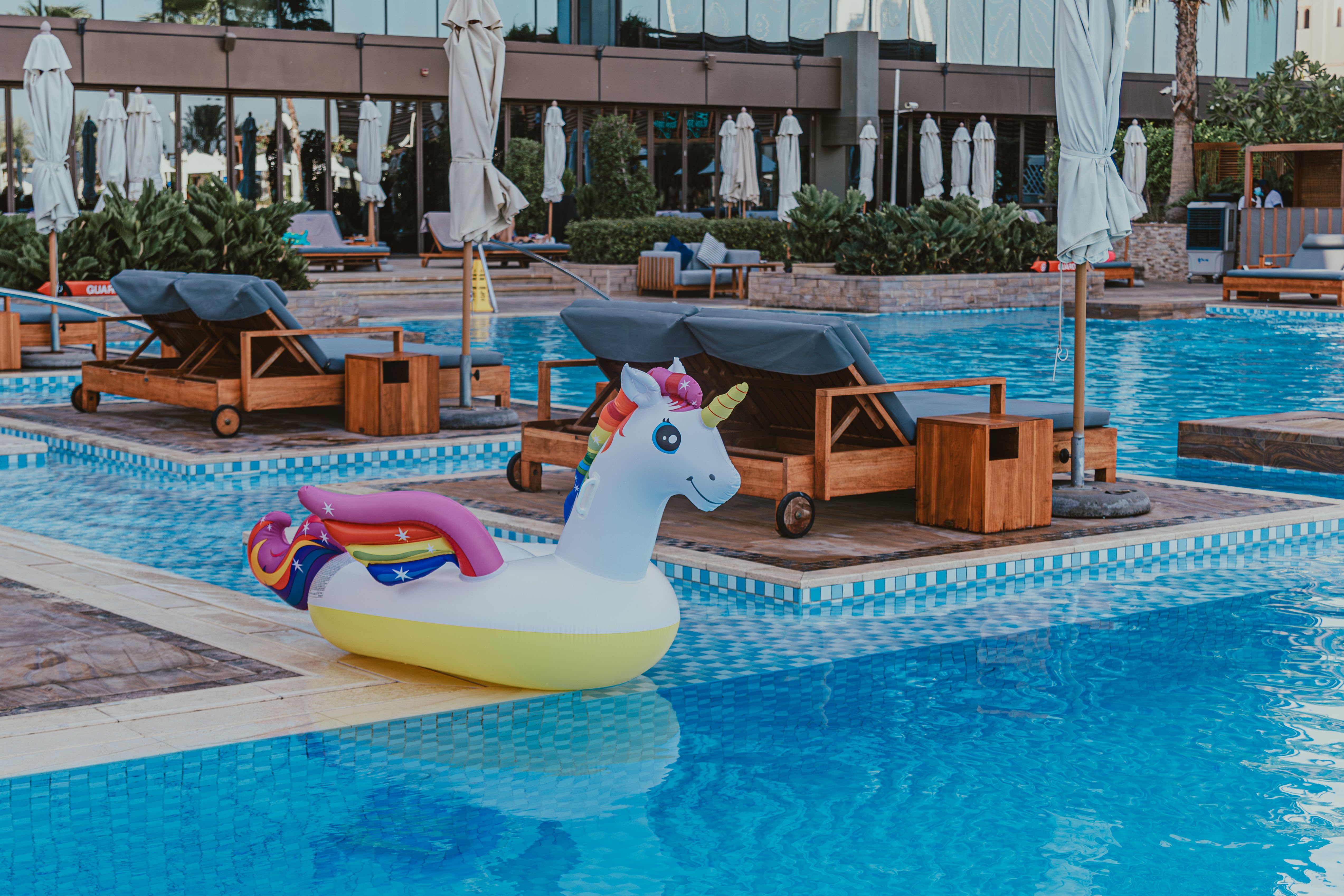 Colorful inflatable unicorn float at a luxury Dubai resort poolside, perfect for vacation relaxation.