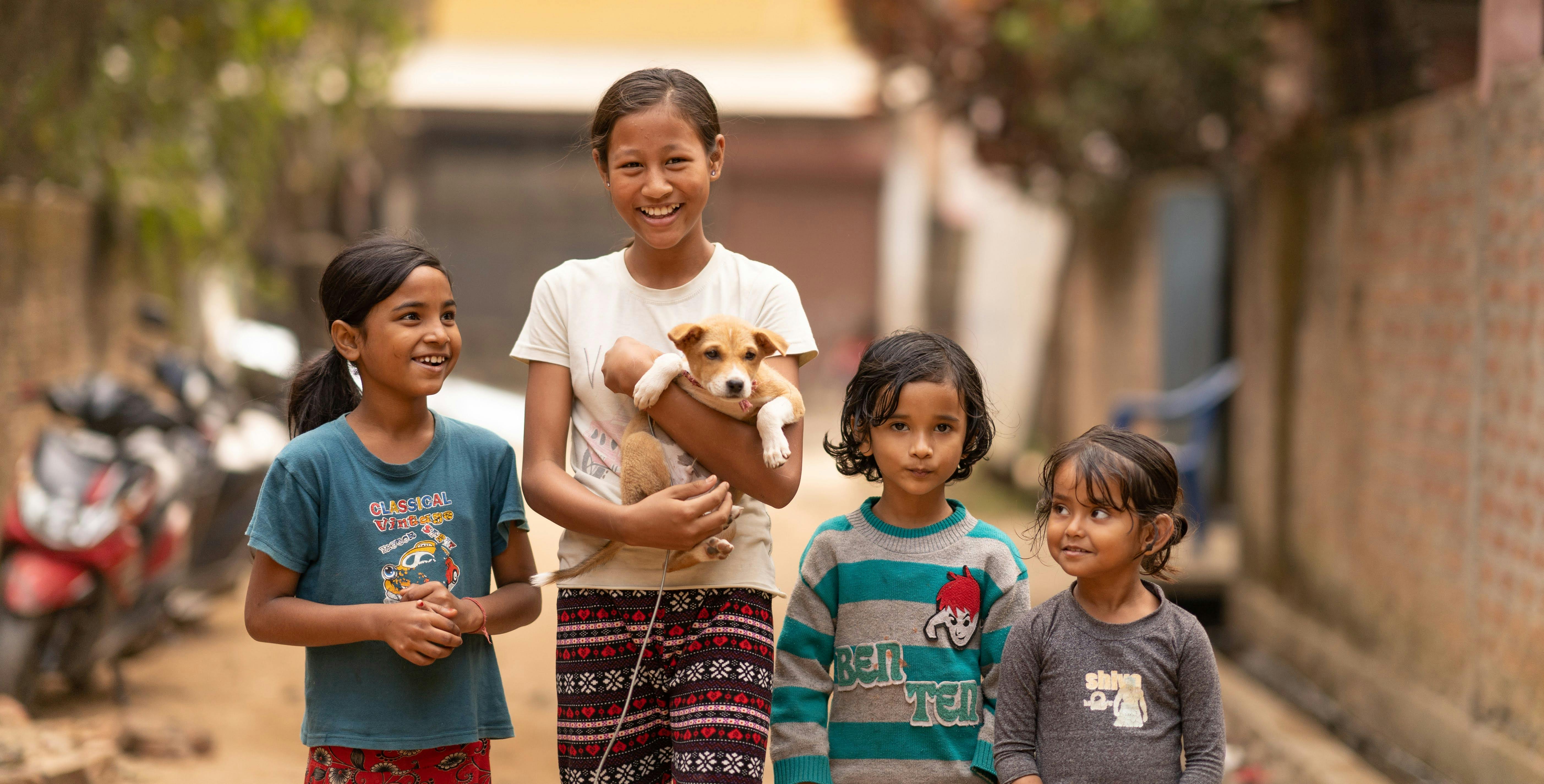 A group of children holding a dog in the street