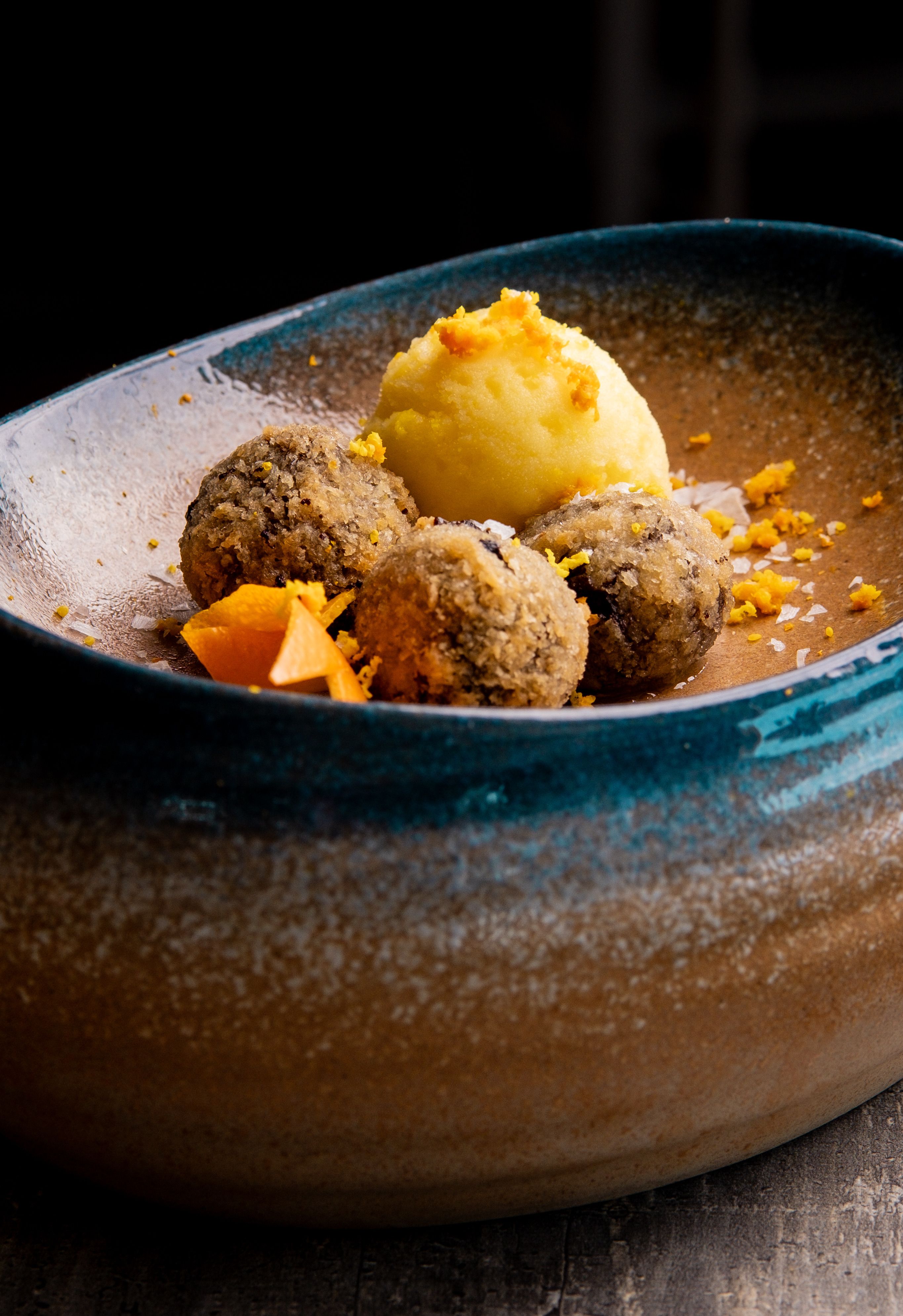 Two mounds of mash on a plate, golden-orange mashed rutabaga next to pale mashed potatoes, both topped with melting butter, served alongside sliced haggis.
