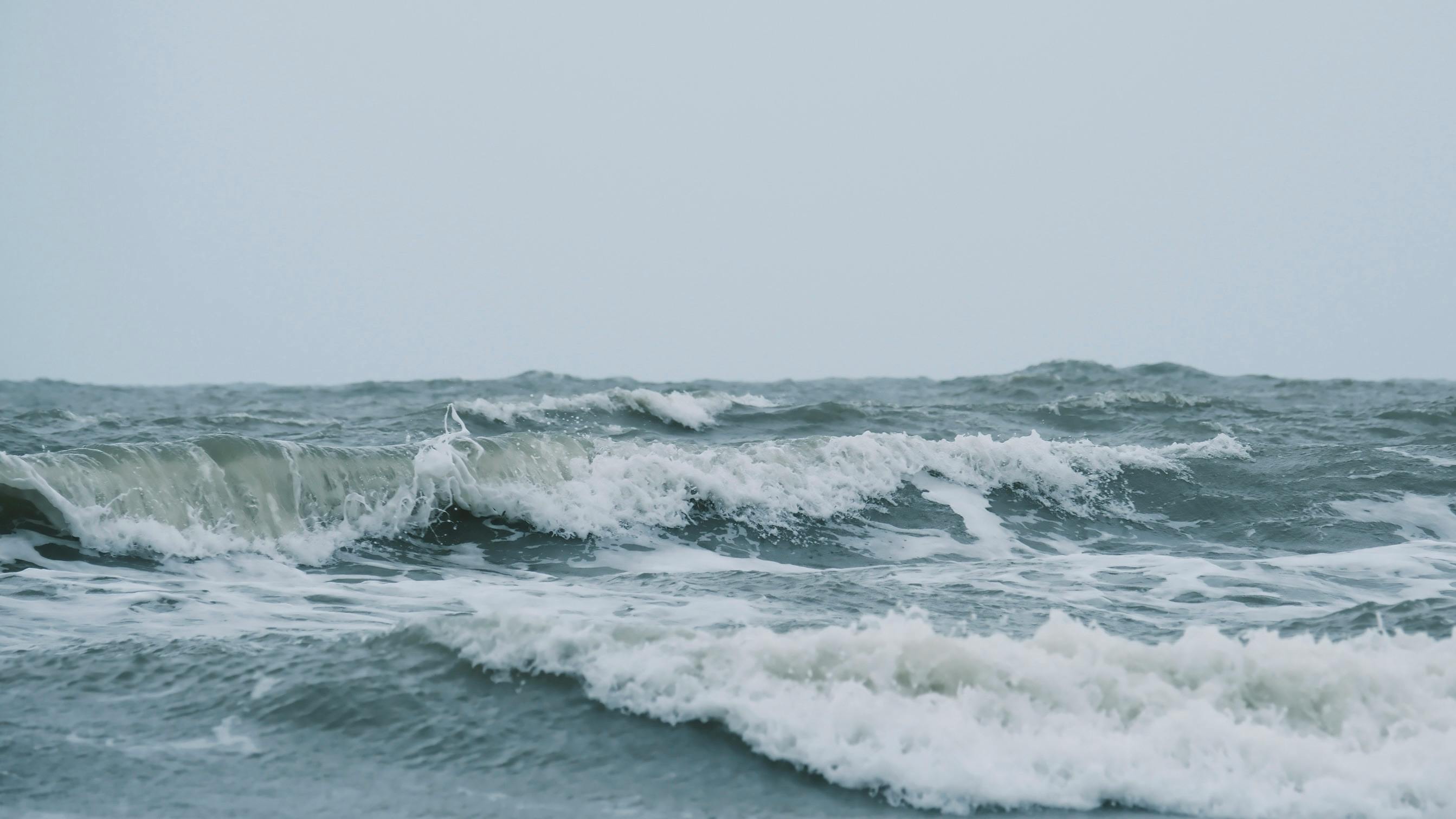 Imagen cautivadora de poderosas olas del océano chocando entre sí en un día tormentoso.