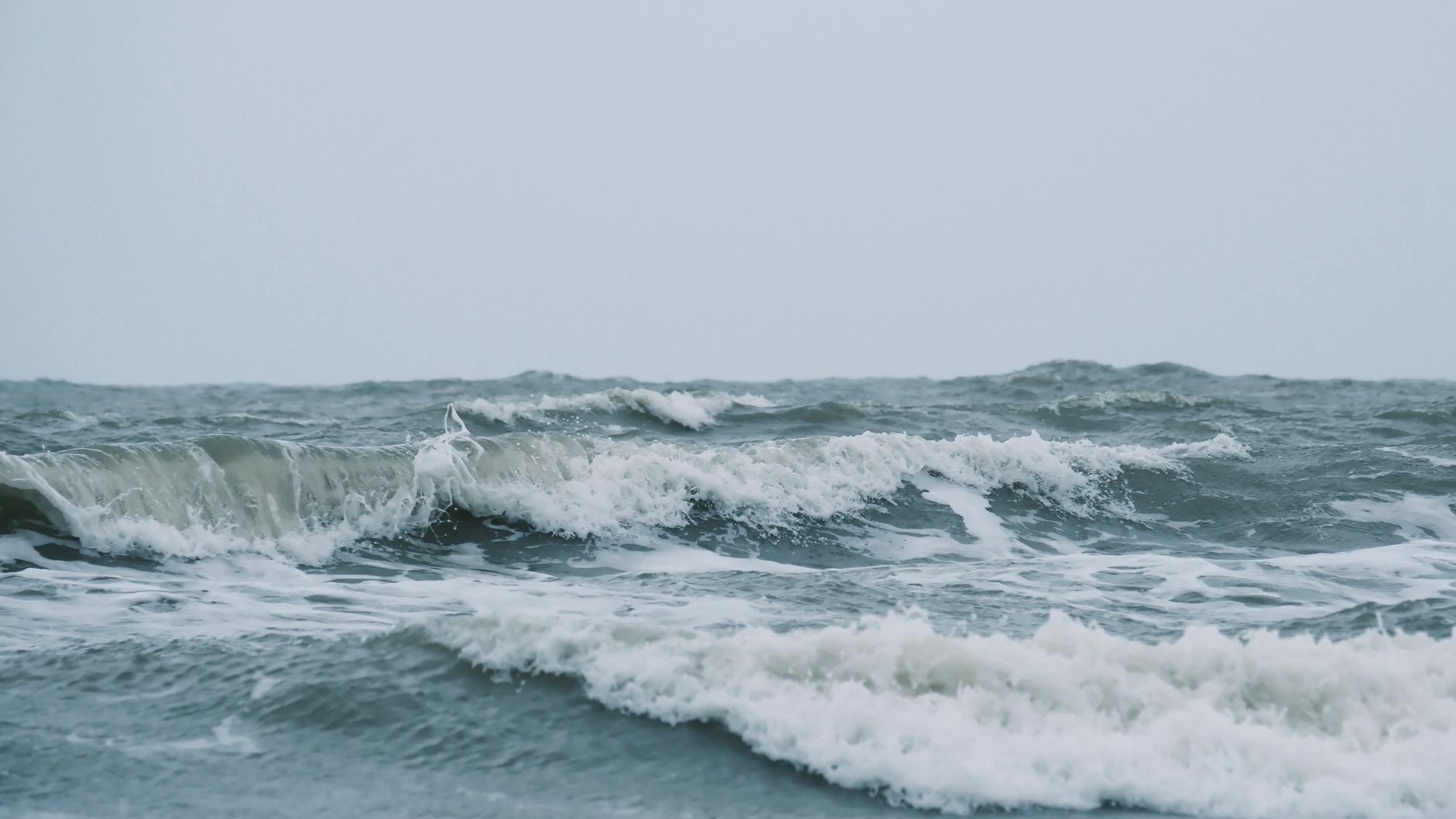 Imagen cautivadora de poderosas olas del océano chocando entre sí en un día tormentoso.