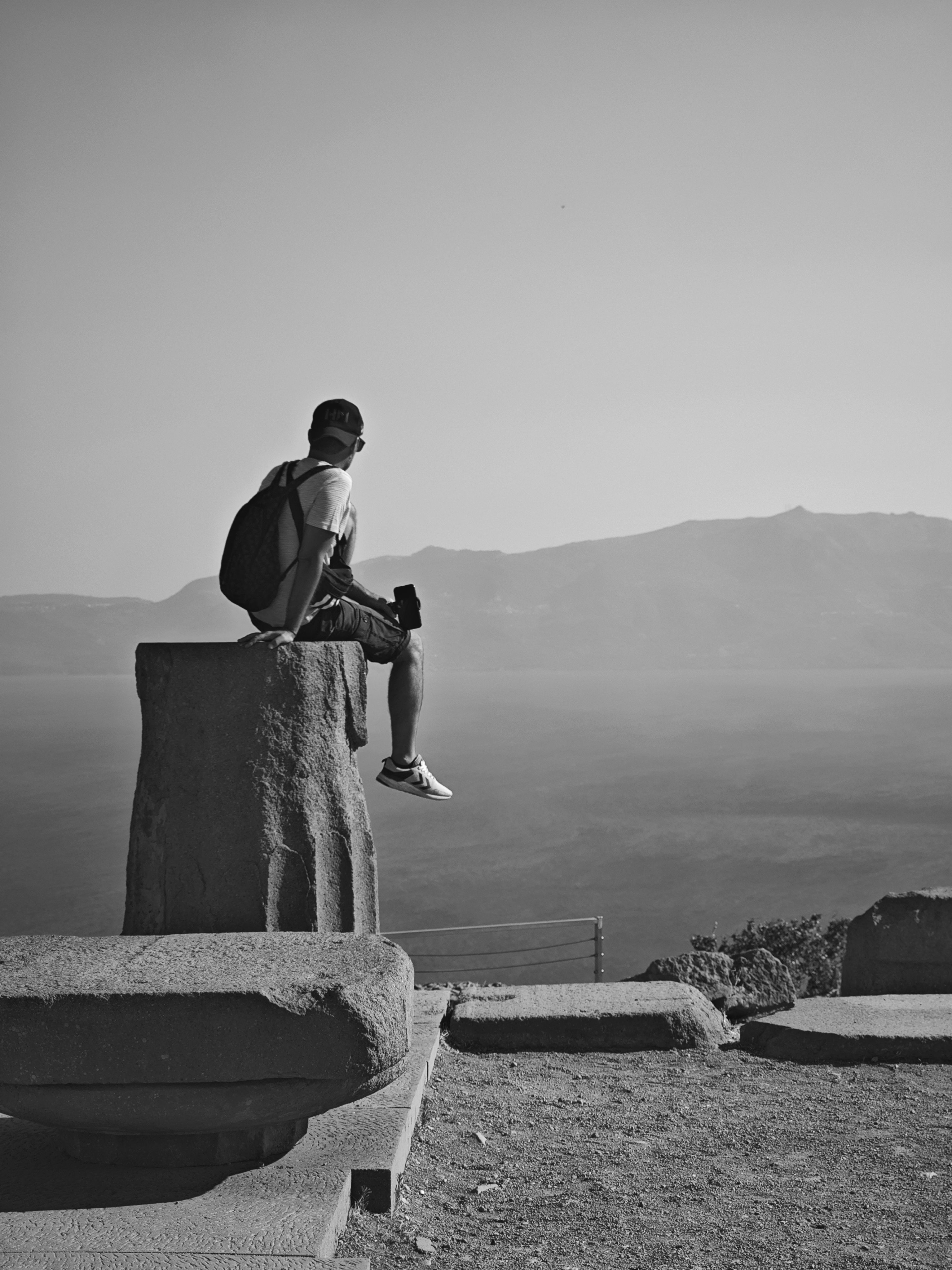A man sitting on a rock looking at the ocean · Free Stock Photo