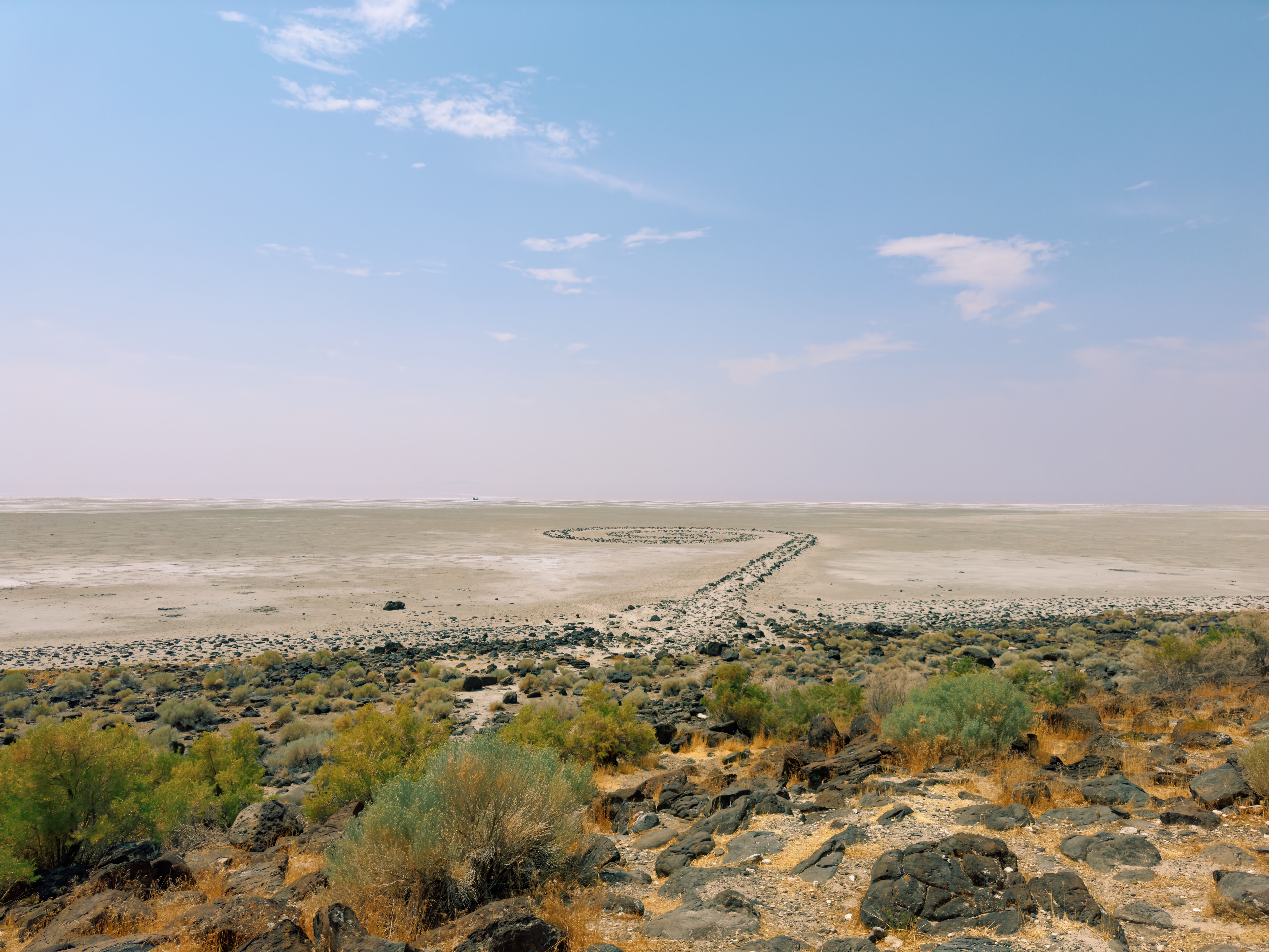 View of the Spiral Jetty art installation in a vast, arid desert landscape.