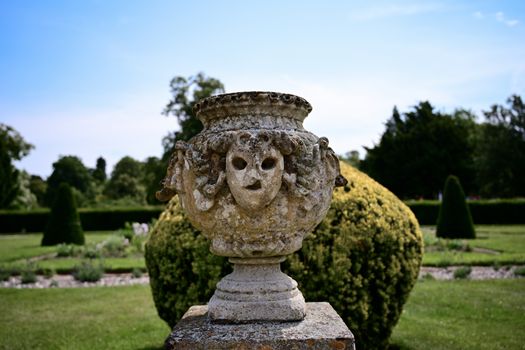 An ancient stone sculpture in a beautiful summer garden, showcasing classical design.