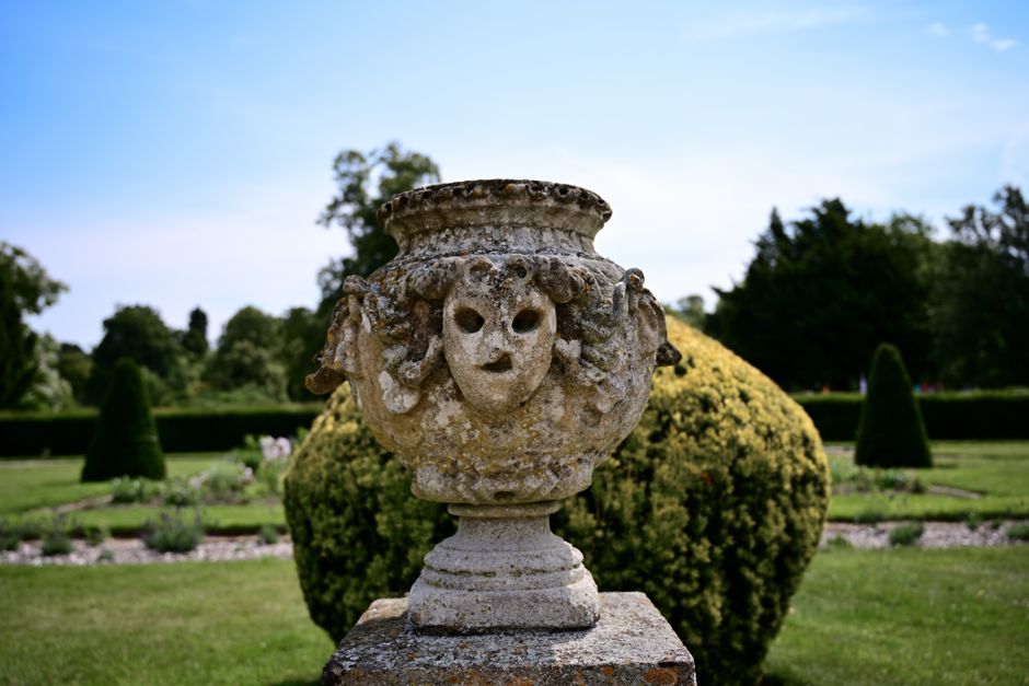 An ancient stone sculpture in a beautiful summer garden, showcasing classical design.