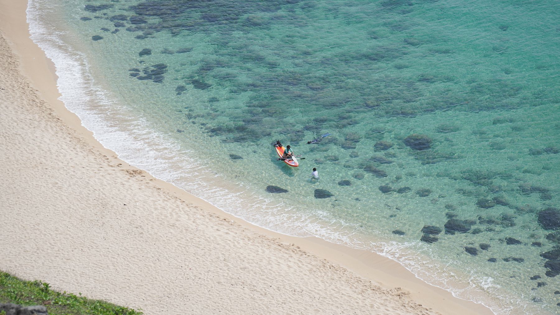 Scenic aerial view of Phan Thiết beach showcasing turquoise water and sandy shore with a canoe and people enjoying the s