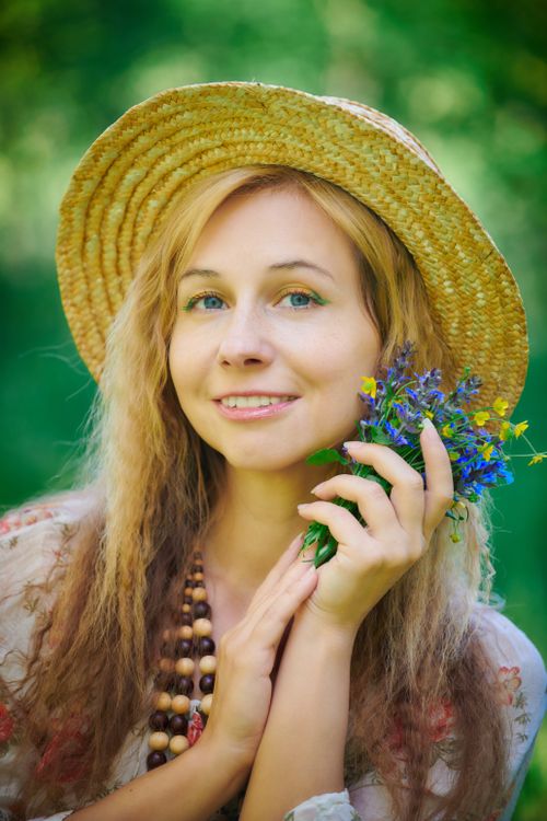 A woman in a straw hat holding flowers · Free Stock Photo