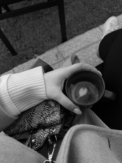 Free Stylish black and white image of a hand holding a coffee cup with heart foam. Stock Photo