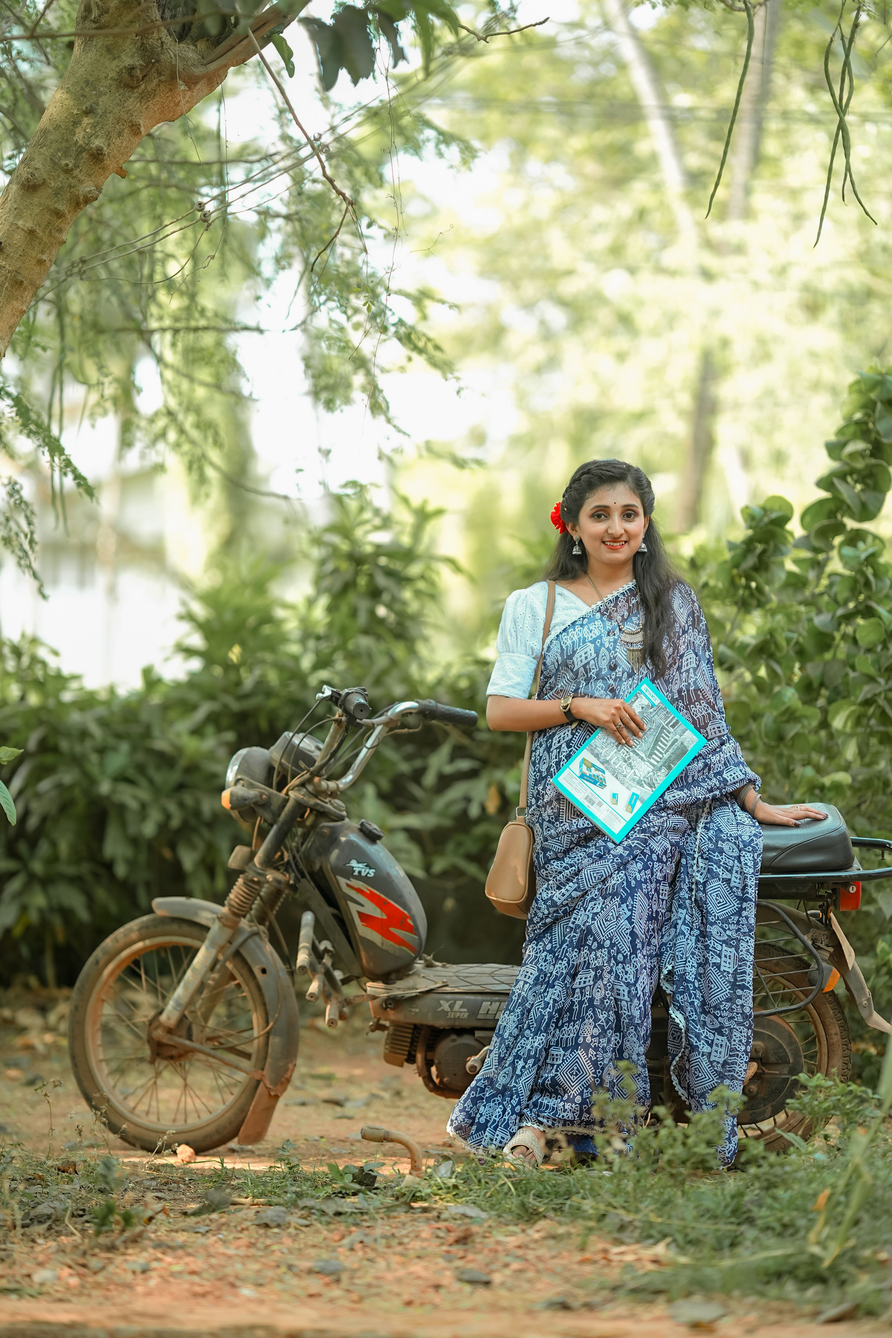 A woman in a blue sari standing next to a motorcycle · Free Stock Photo