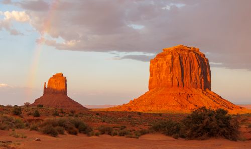 Free Breathtaking view of Monument Valley's buttes illuminated by the sunset with a faint rainbow. Stock Photo