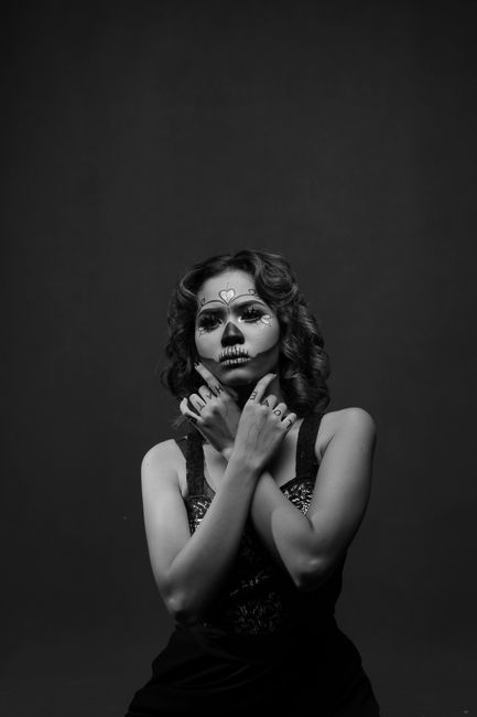 A dramatic black and white portrait featuring a woman with artistic face paint in a studio setting.