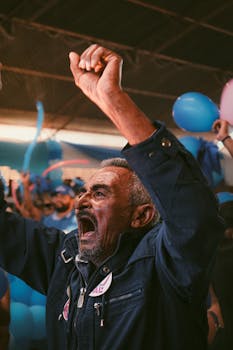 Senior man passionately cheering at a colorful festival in Brazil, surrounded by balloons.