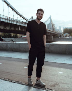 桥旁一位男子随意微笑的城市肖像，展现了现代时尚与风格