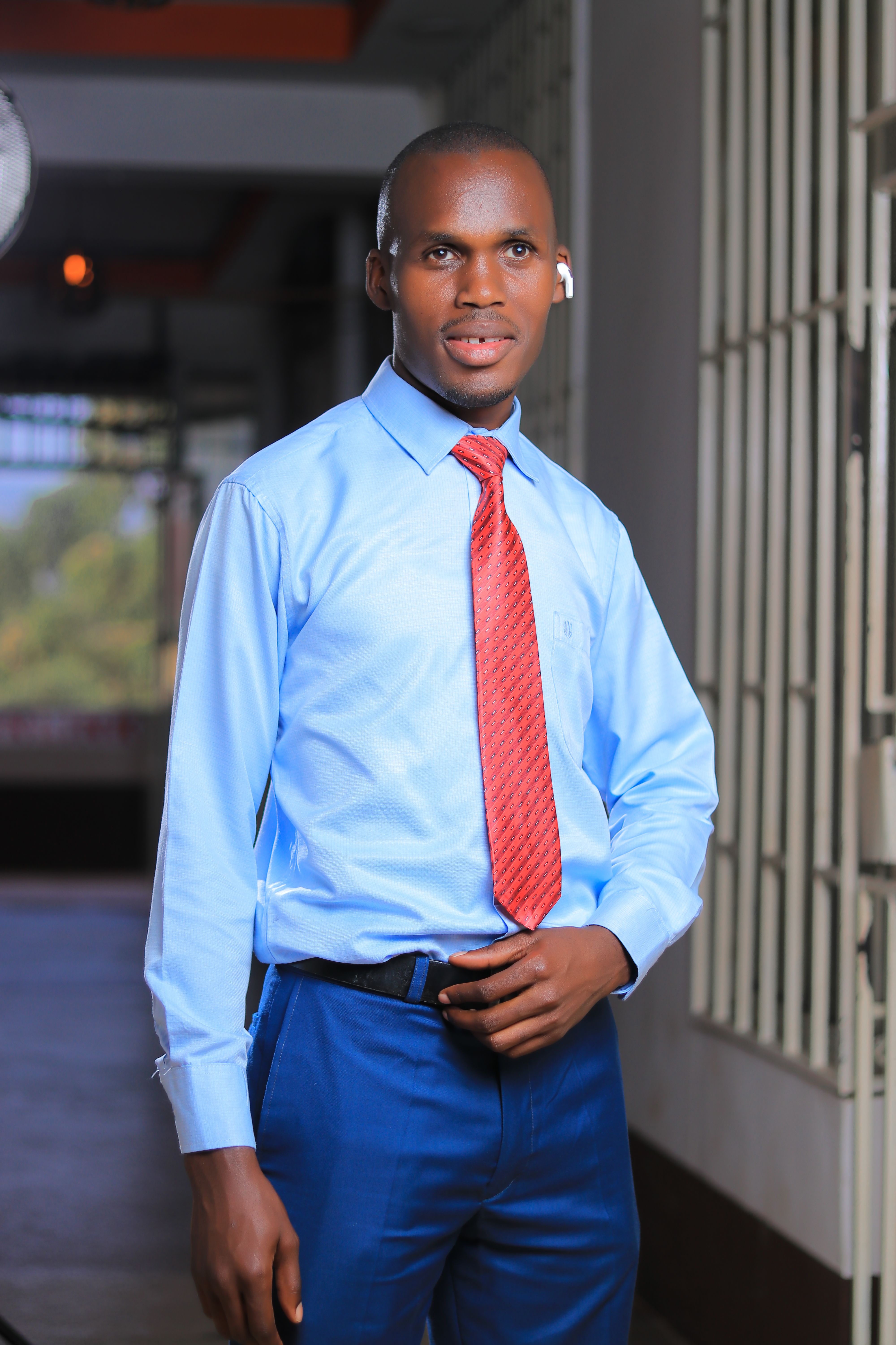 Portrait of a confident businessman in formal attire standing indoors, wearing a blue shirt and red tie.