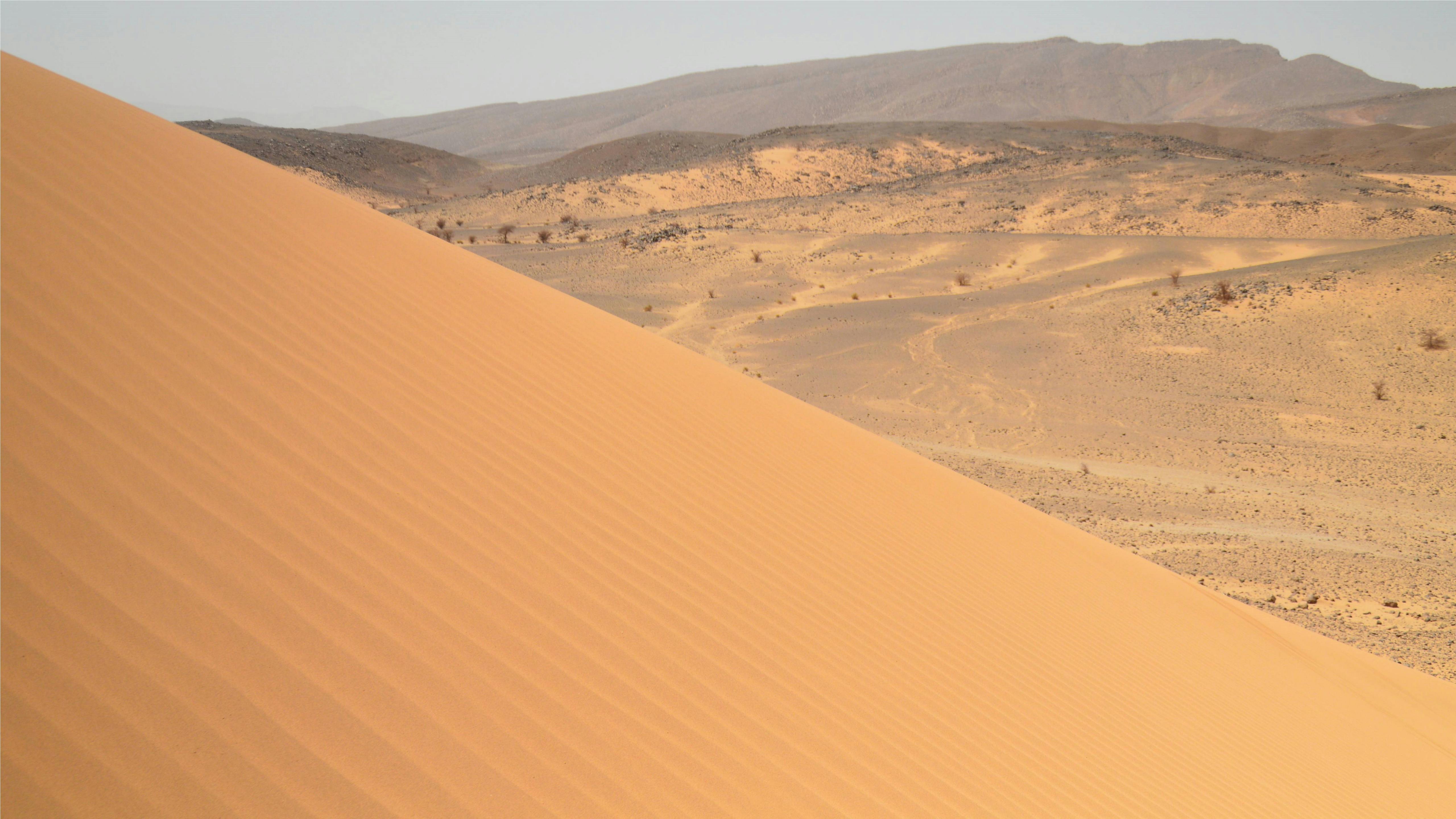 a person walking on a sand dune in the desert