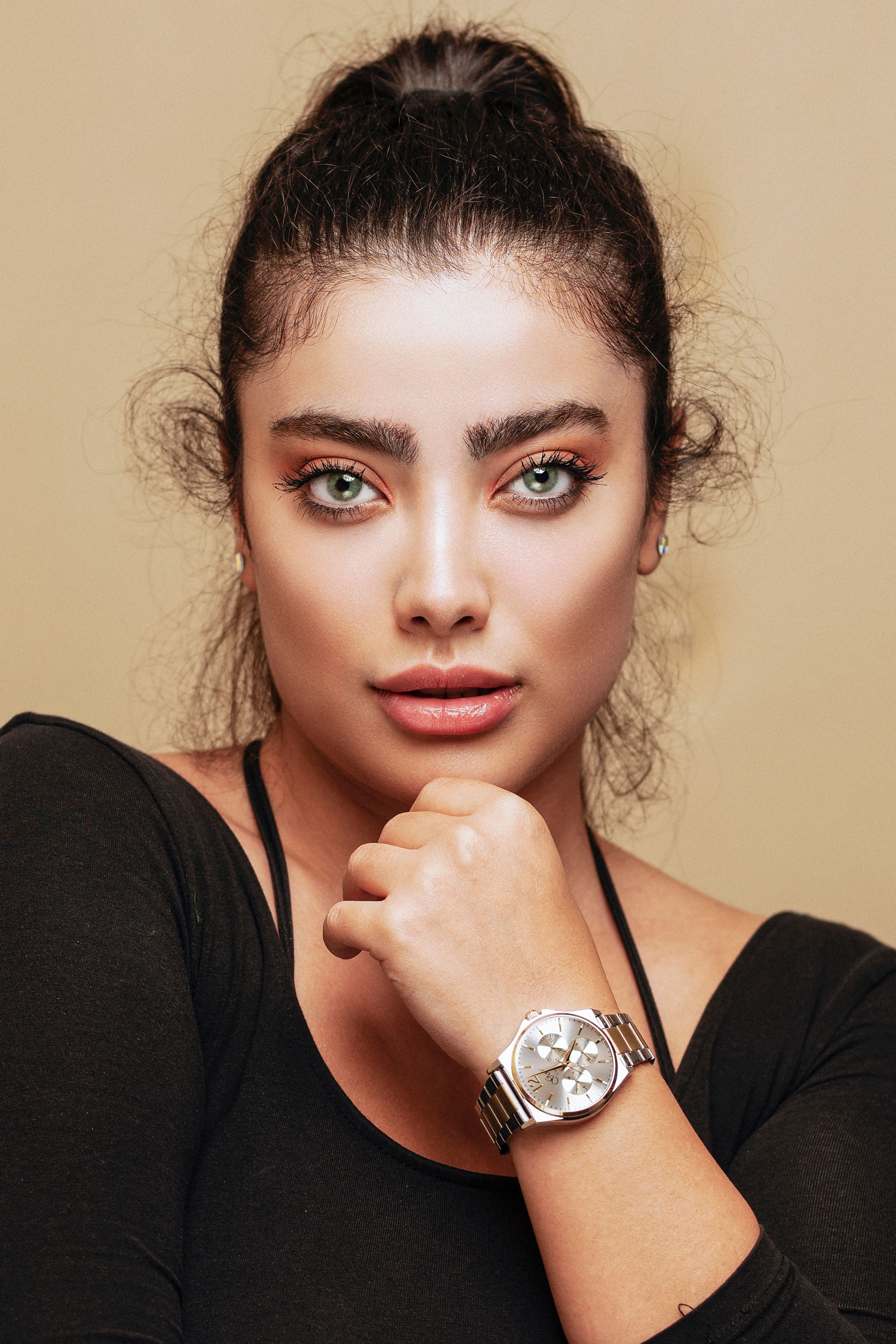 A captivating portrait of a fashionable woman with striking eyes, showcasing confidence and style in her unique watch and elegant attire.