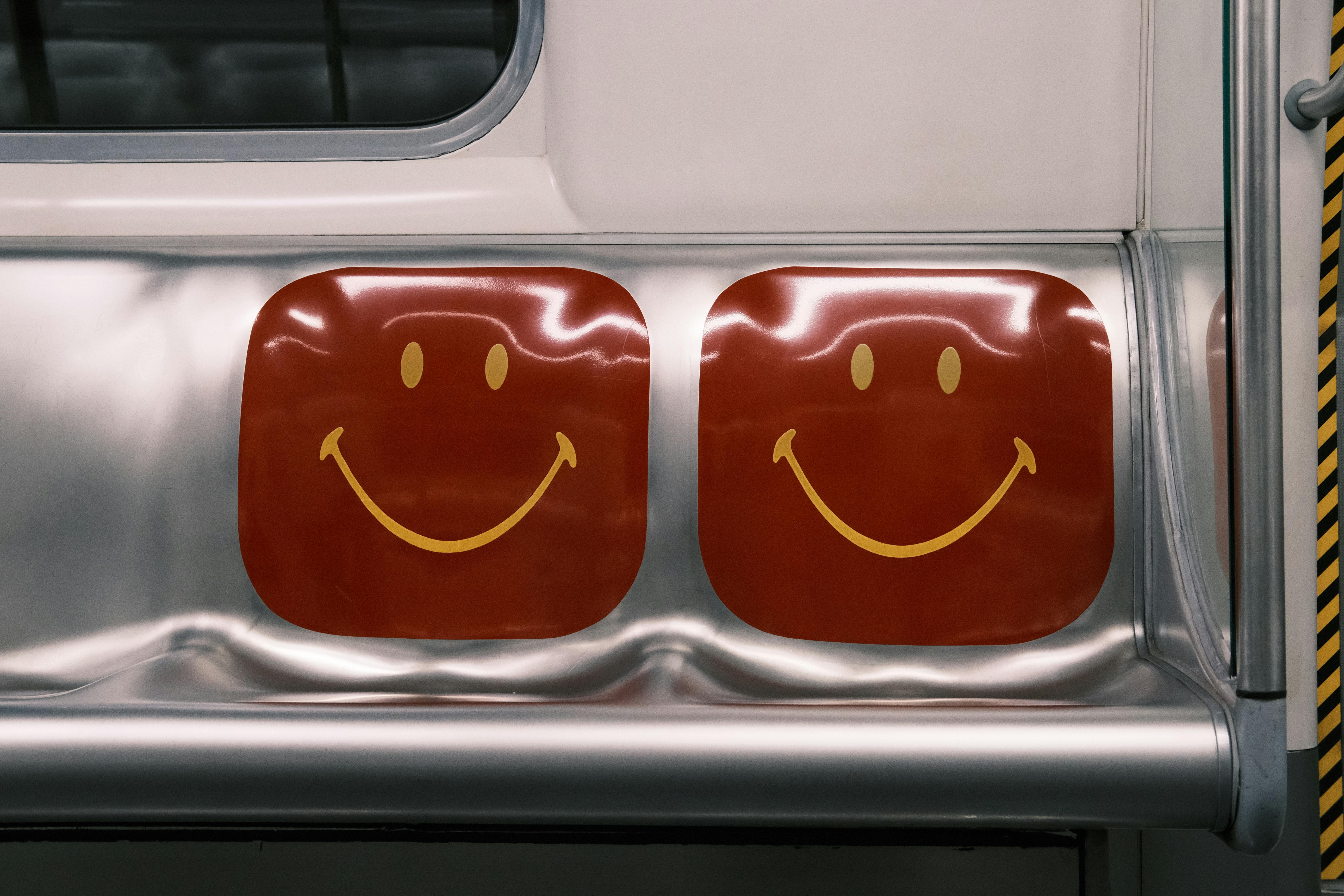Bright red smiley face design on shiny metal train seat, capturing retro style.