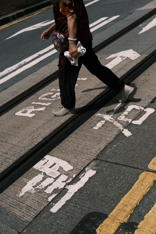 Free A person crossing a marked urban road, featuring directional signs and pavement markings. Stock Photo