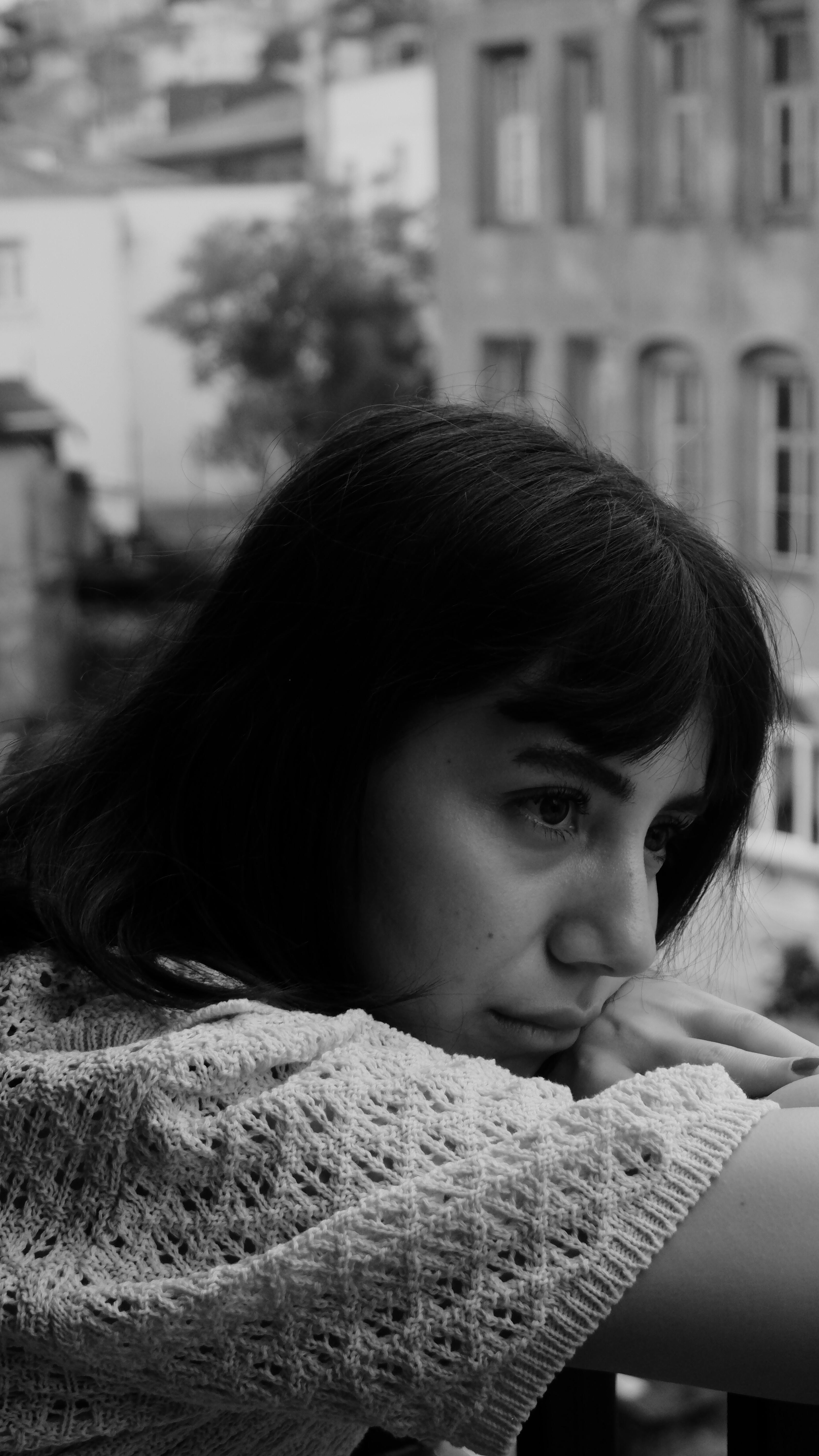 Woman in thoughtful black and white profile portrait by a window.