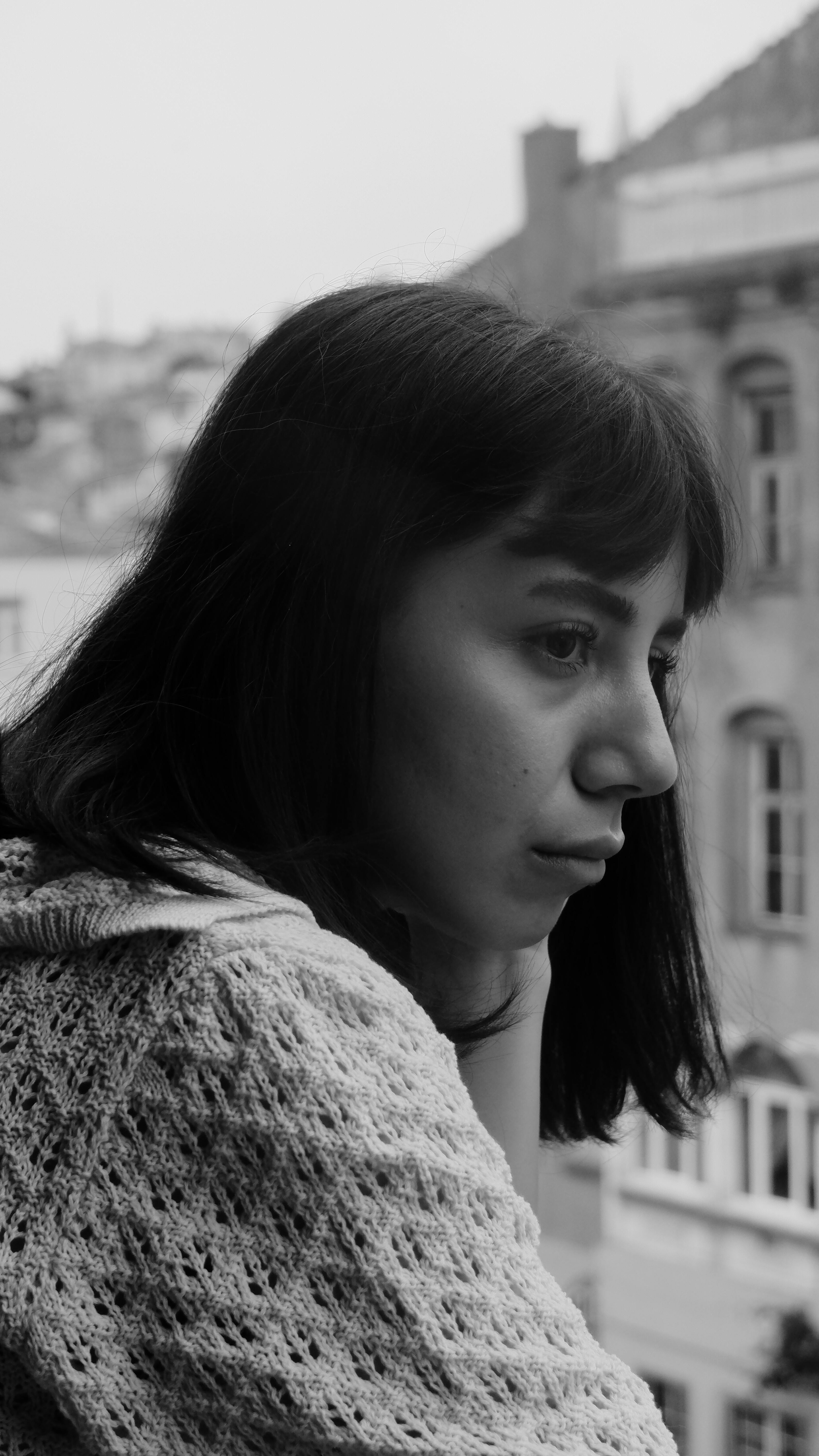 A monochromatic portrait of a woman in deep thought, gazing out from a balcony.