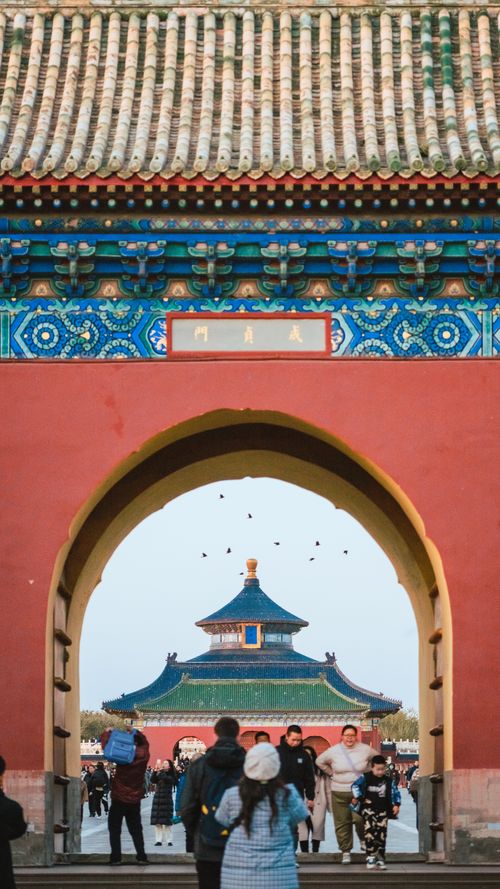 Free View of the Temple of Heaven in Beijing through a traditional gate with visitors present. Stock Photo