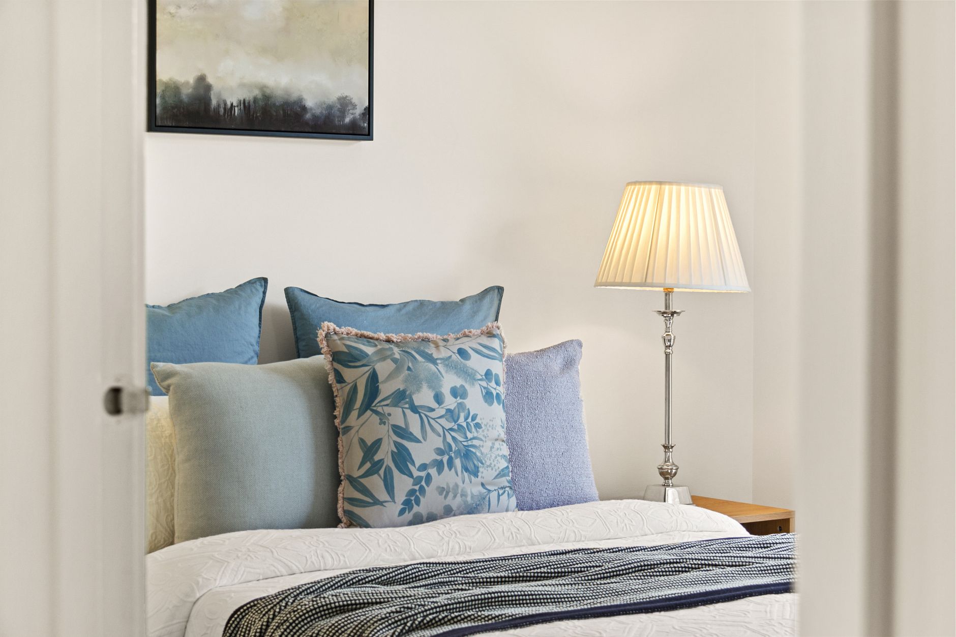 A serene bedroom featuring elegant decor, plush cushions, and soft lamp lighting for a cozy ambiance.