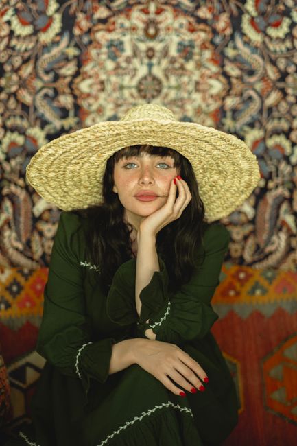 Artistic portrait of a woman with a straw hat against a colorful background, showcasing fashion and style.