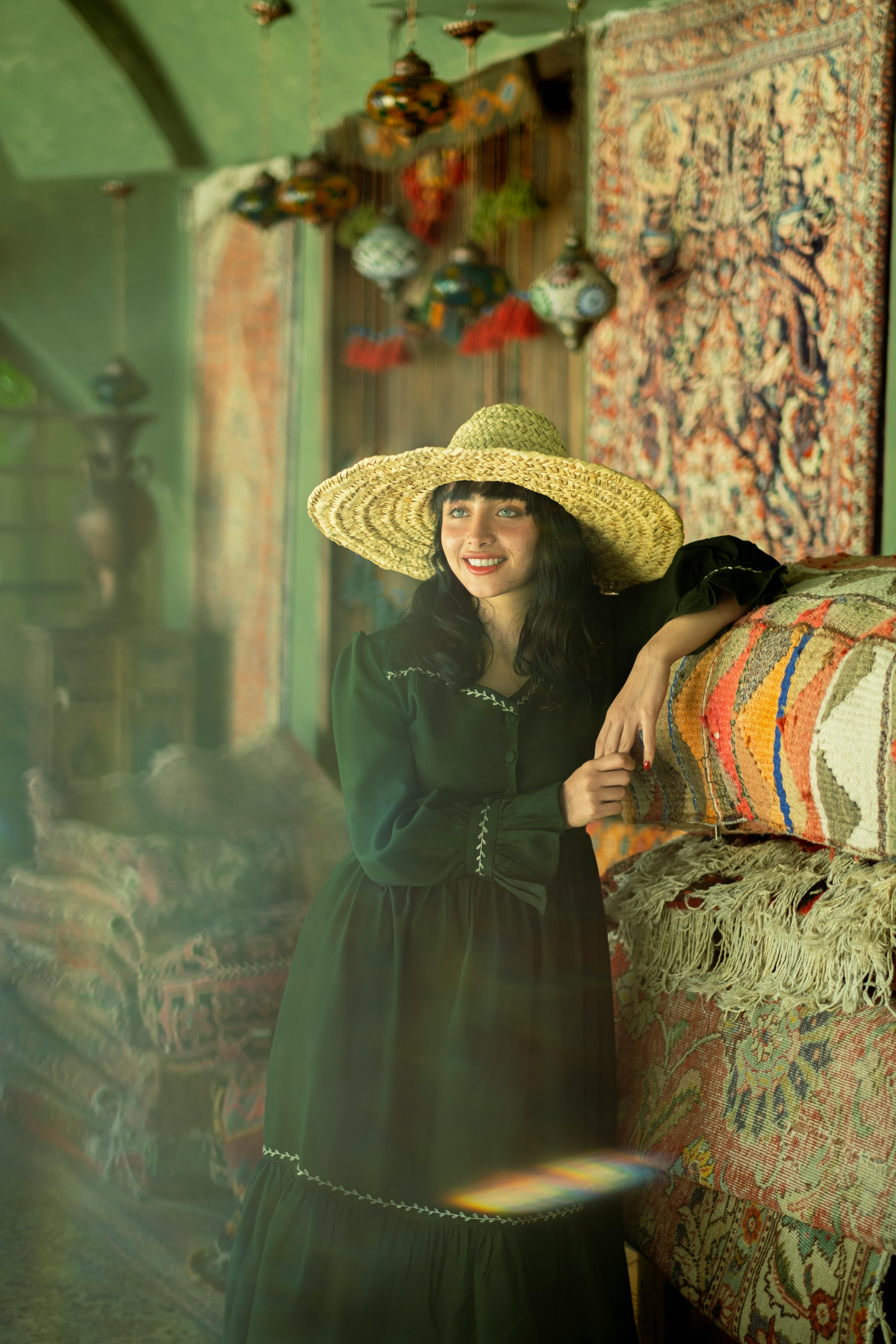 a woman in a hat and dress standing in front of a rug