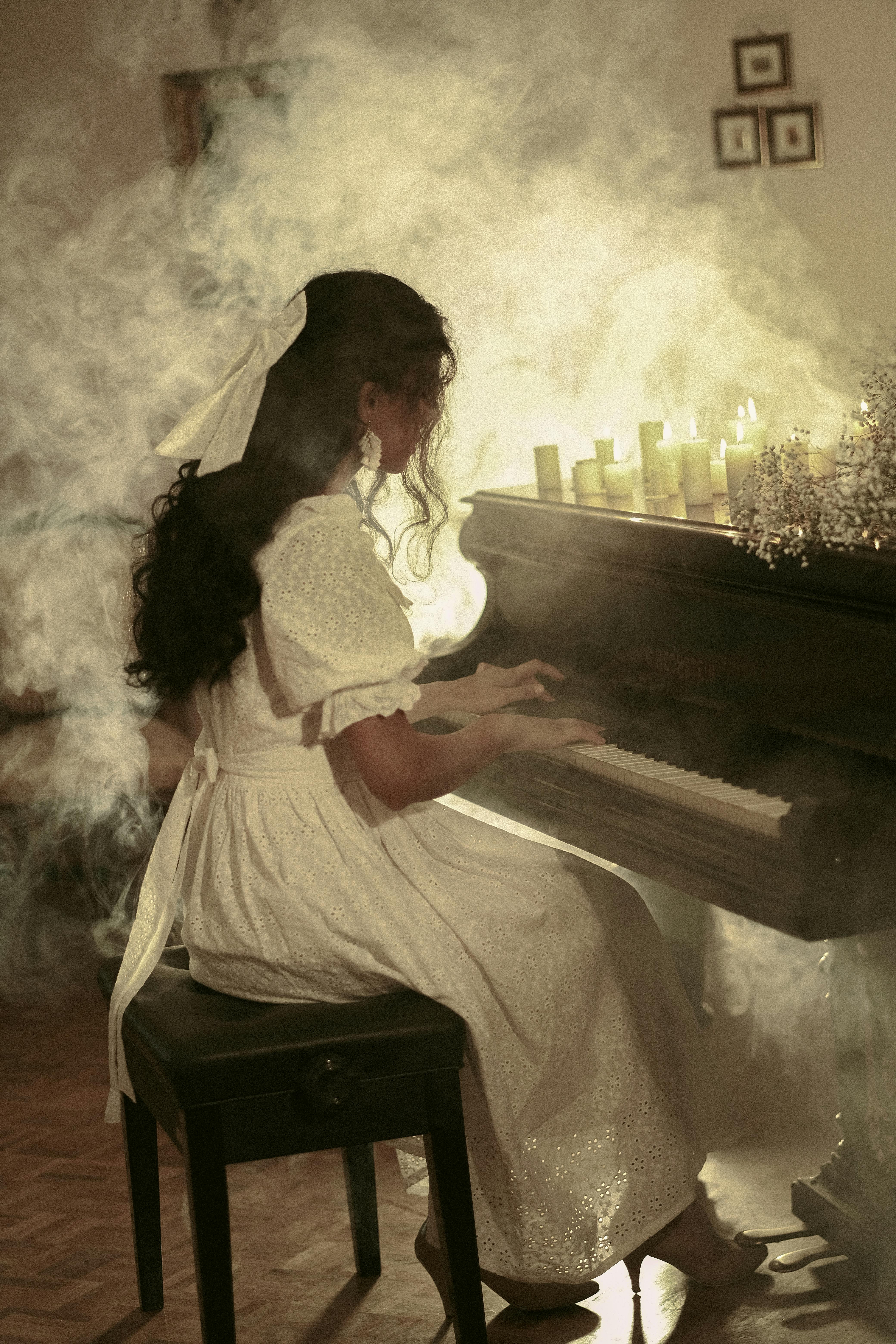A woman playing the piano in a room with smoke · Free Stock Photo