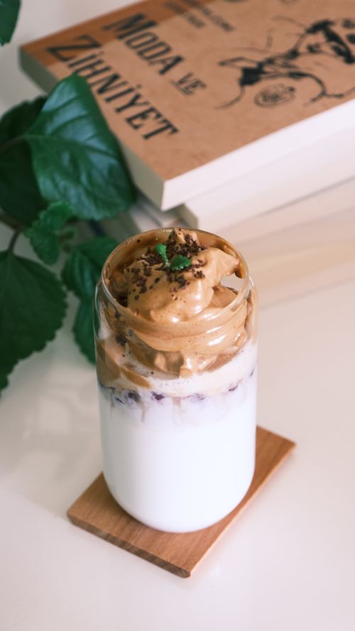 Free Creamy dalgona coffee in a glass atop a wooden coaster, perfect for breakfast indulgence. Stock Photo