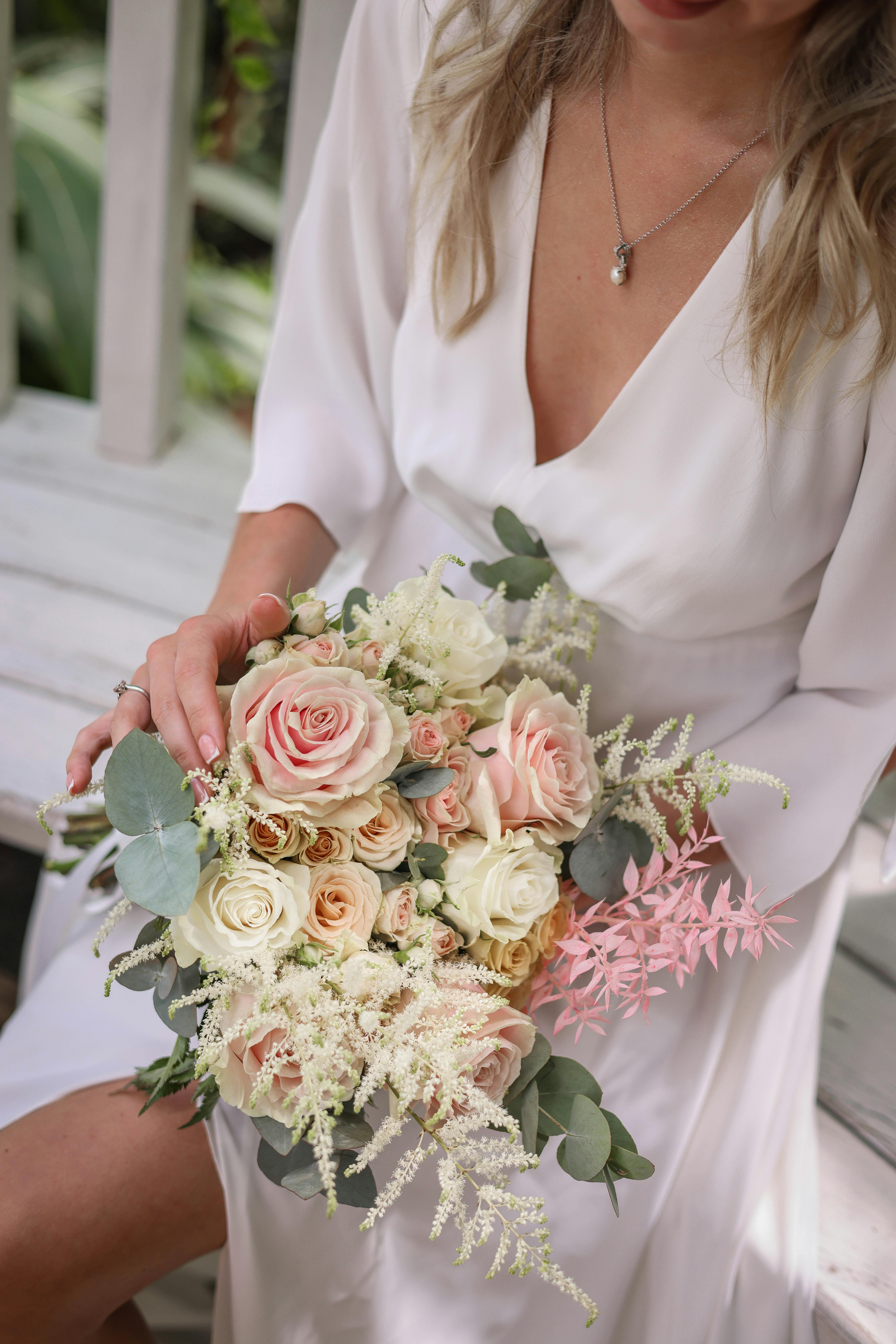 A bride holding an elegant bouquet of roses and greenery, perfect for a romantic wedding.