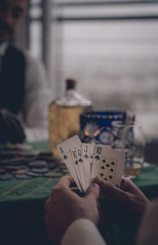 Close-up of spades royal flush in poker game, focus on cards and blurred background setting.