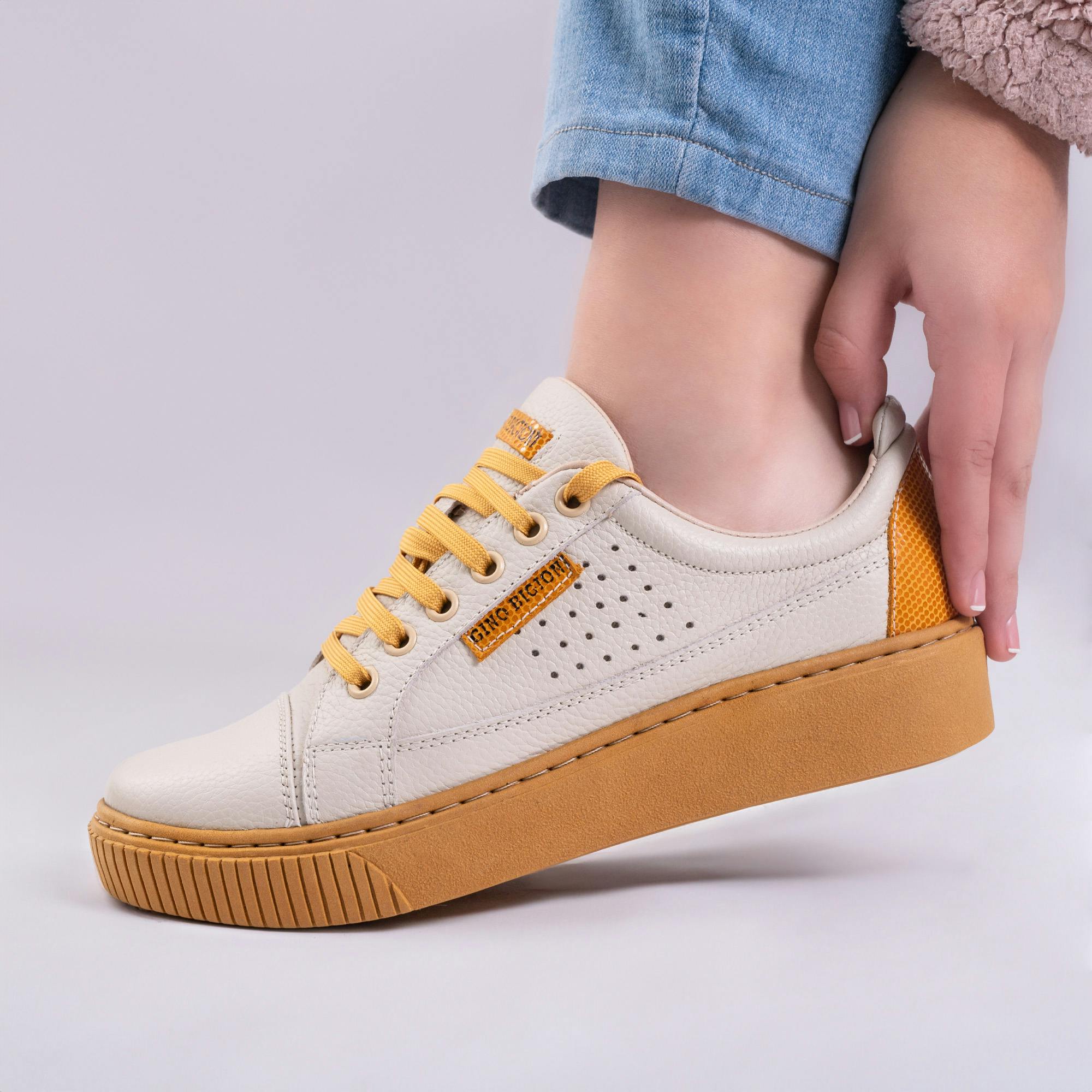Close-up of a woman's hand and trendy mustard sneakers, perfect for casual fashion.