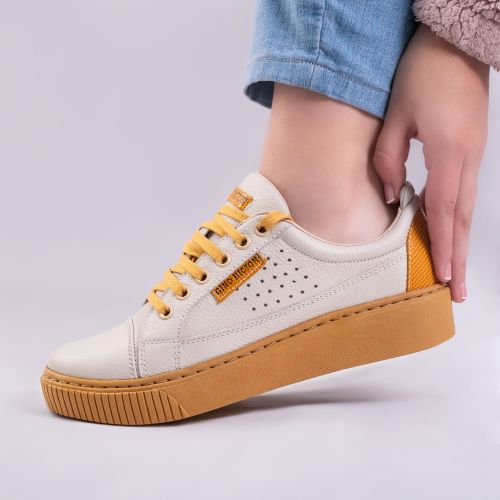 Free Close-up of a woman's hand and trendy mustard sneakers, perfect for casual fashion. Stock Photo
