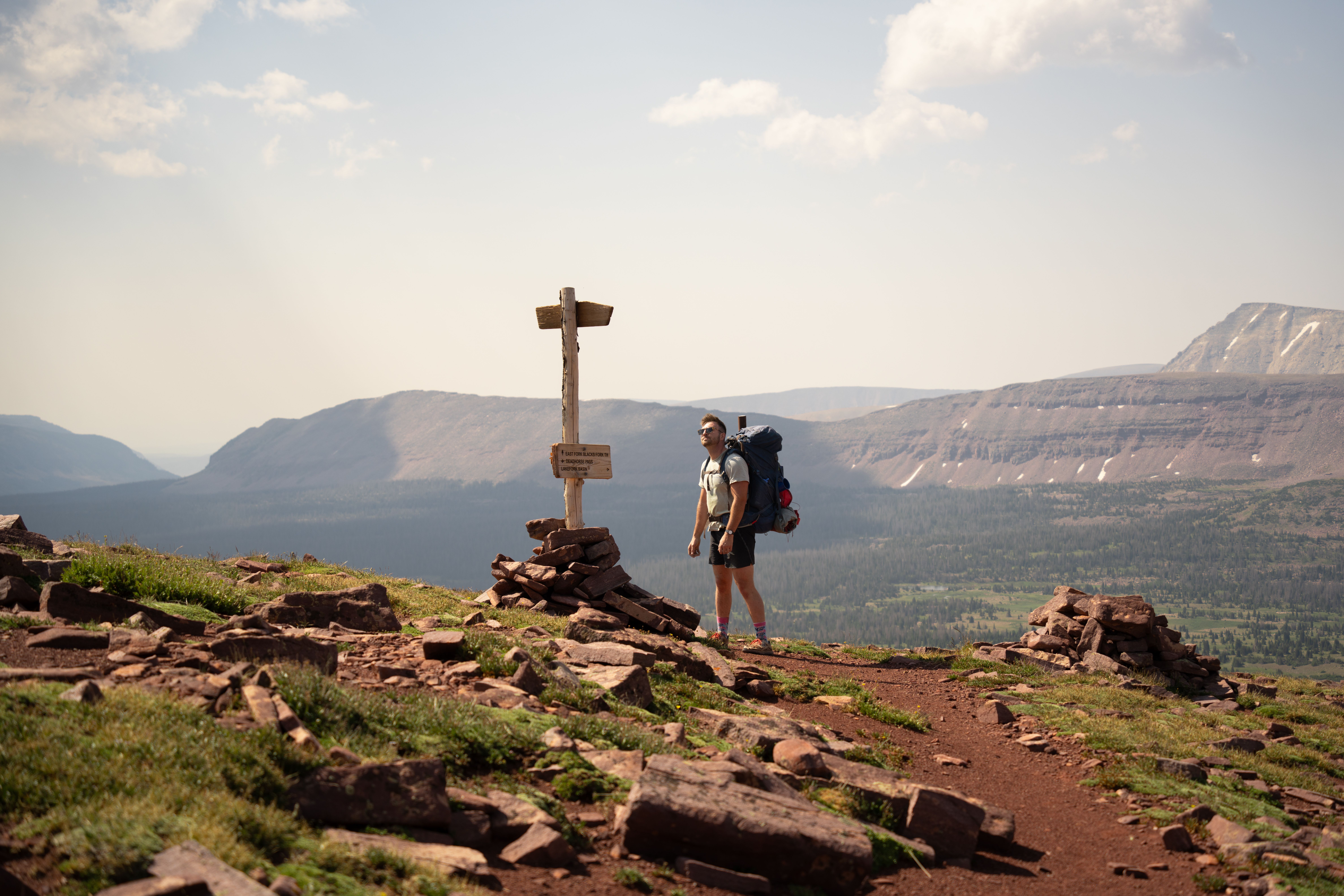 Backpacker with full gear walking along mountain trail during sunset